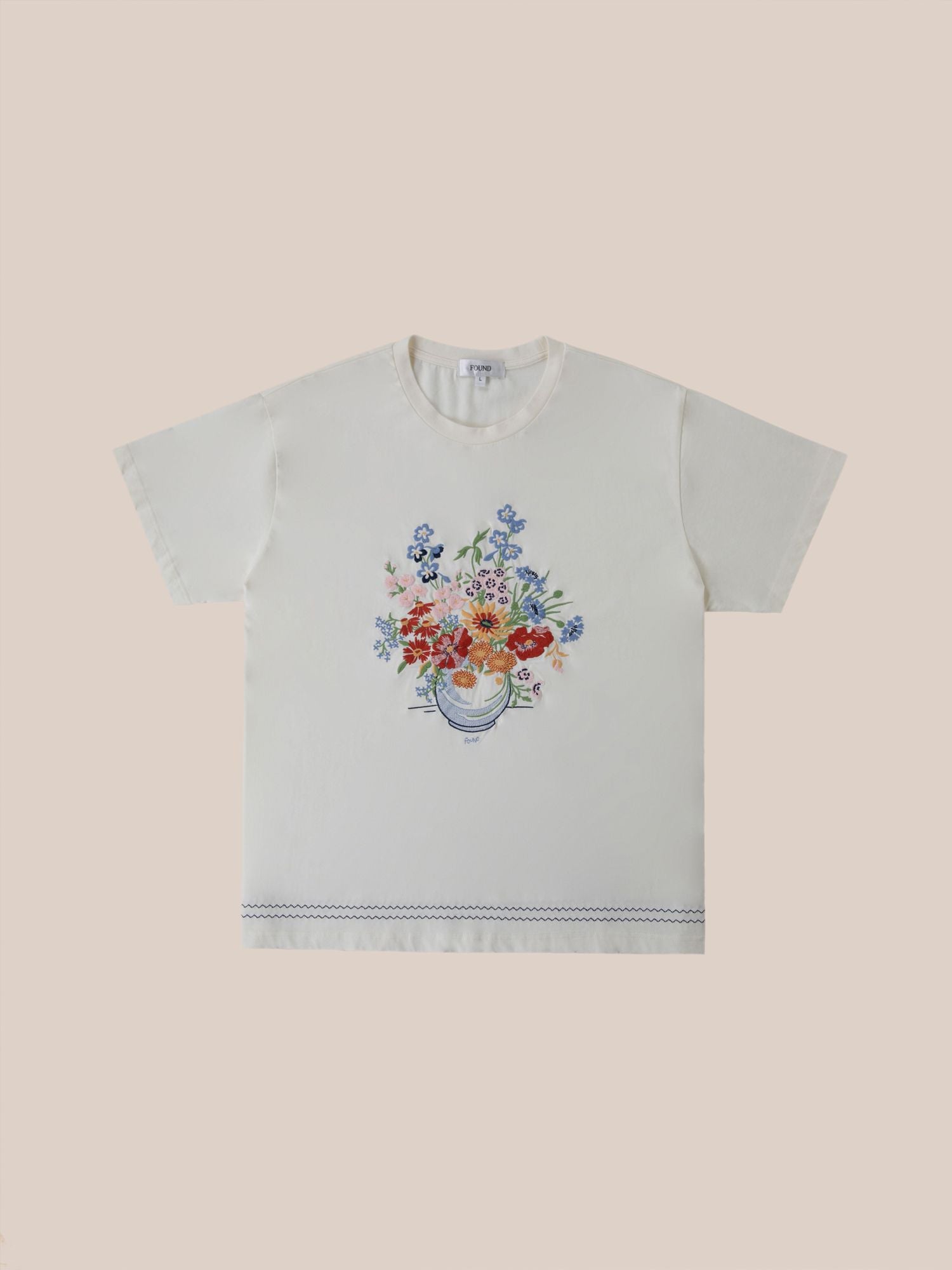 White Bouquet Flowers Tee with colorful Phulkari embroidery centered on the chest, displayed against a light pink background by Found.