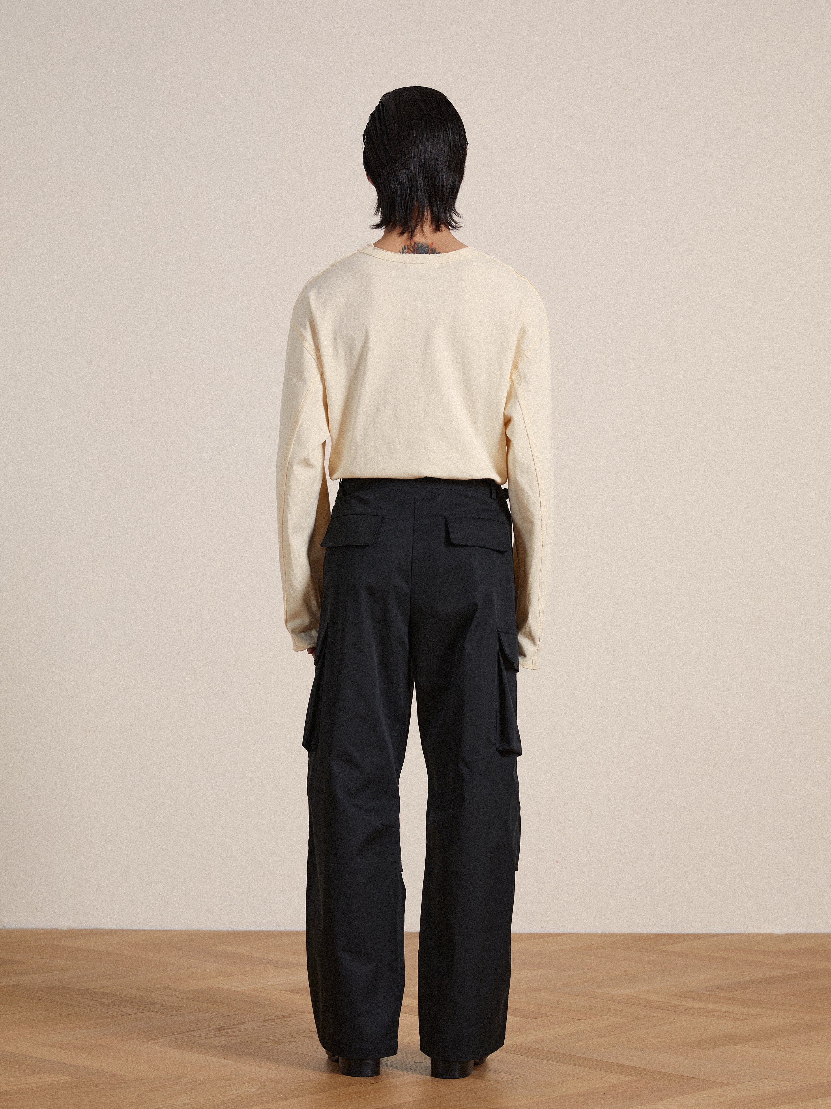 The back view of a man wearing black Found Elbas Cargo Pants with adjustable waist tabs.