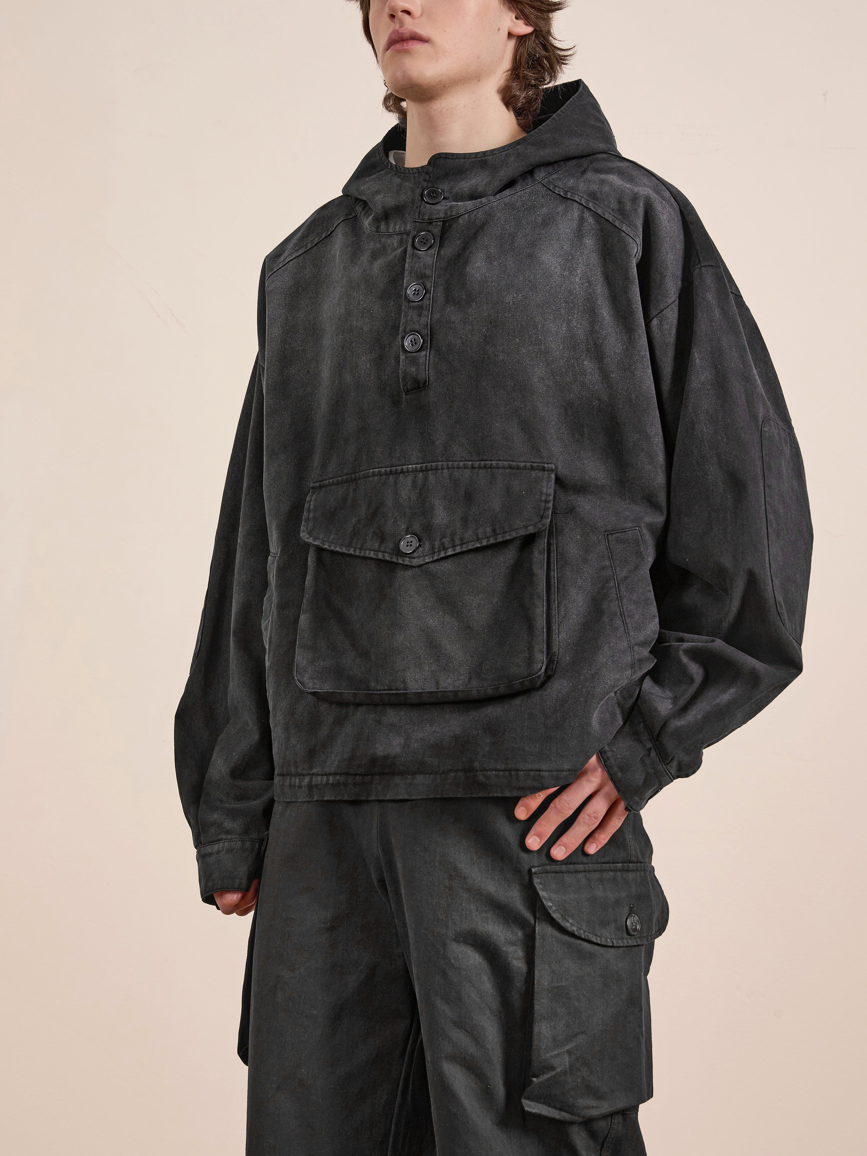 Wearing a FOUND unisex relaxed fit dark Washed Twill Pocket Anorak Jacket with buttons and a large front pocket, paired with matching cargo pants.