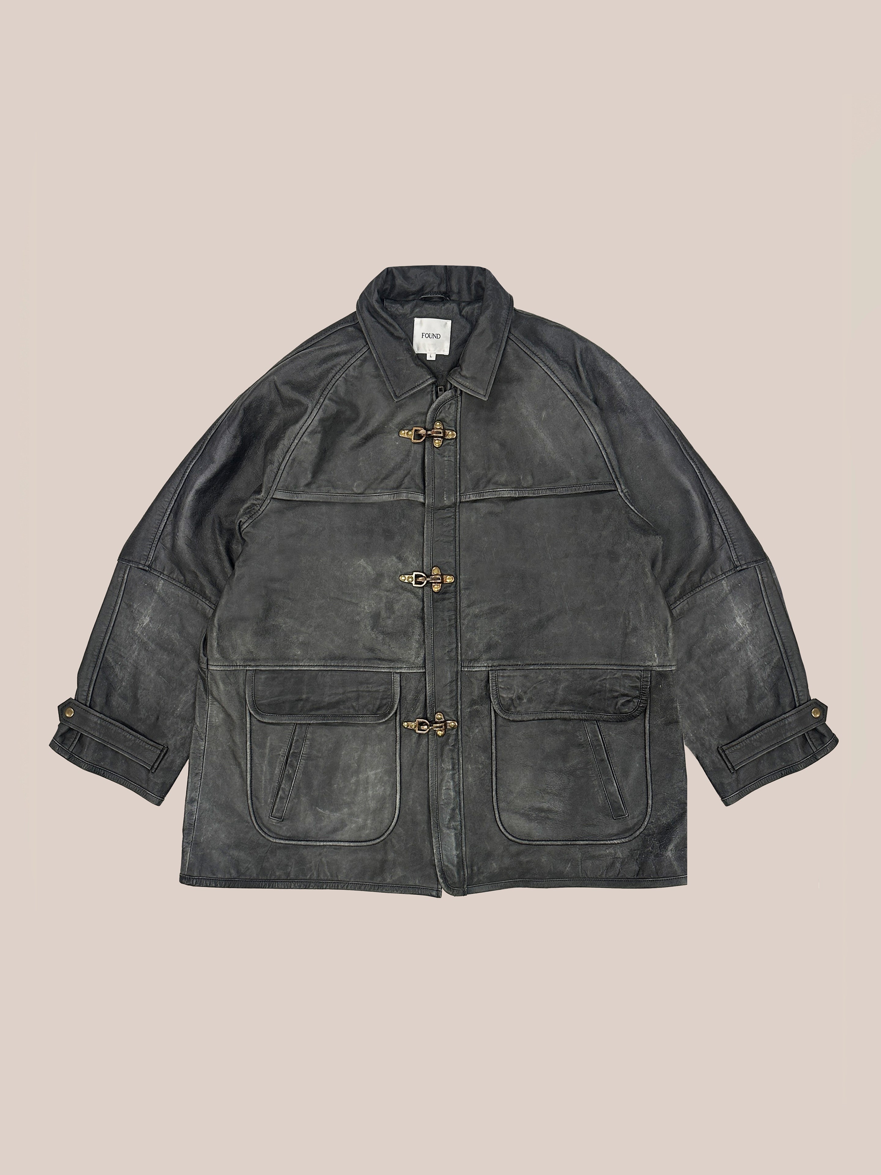 The FOUND Distressed Leather Fireman Clasp Jacket is a classic unisex black leather jacket with a collar, toggle fastenings, buttoned cuffs, and two front pockets, crafted in genuine leather with a weathered finish.