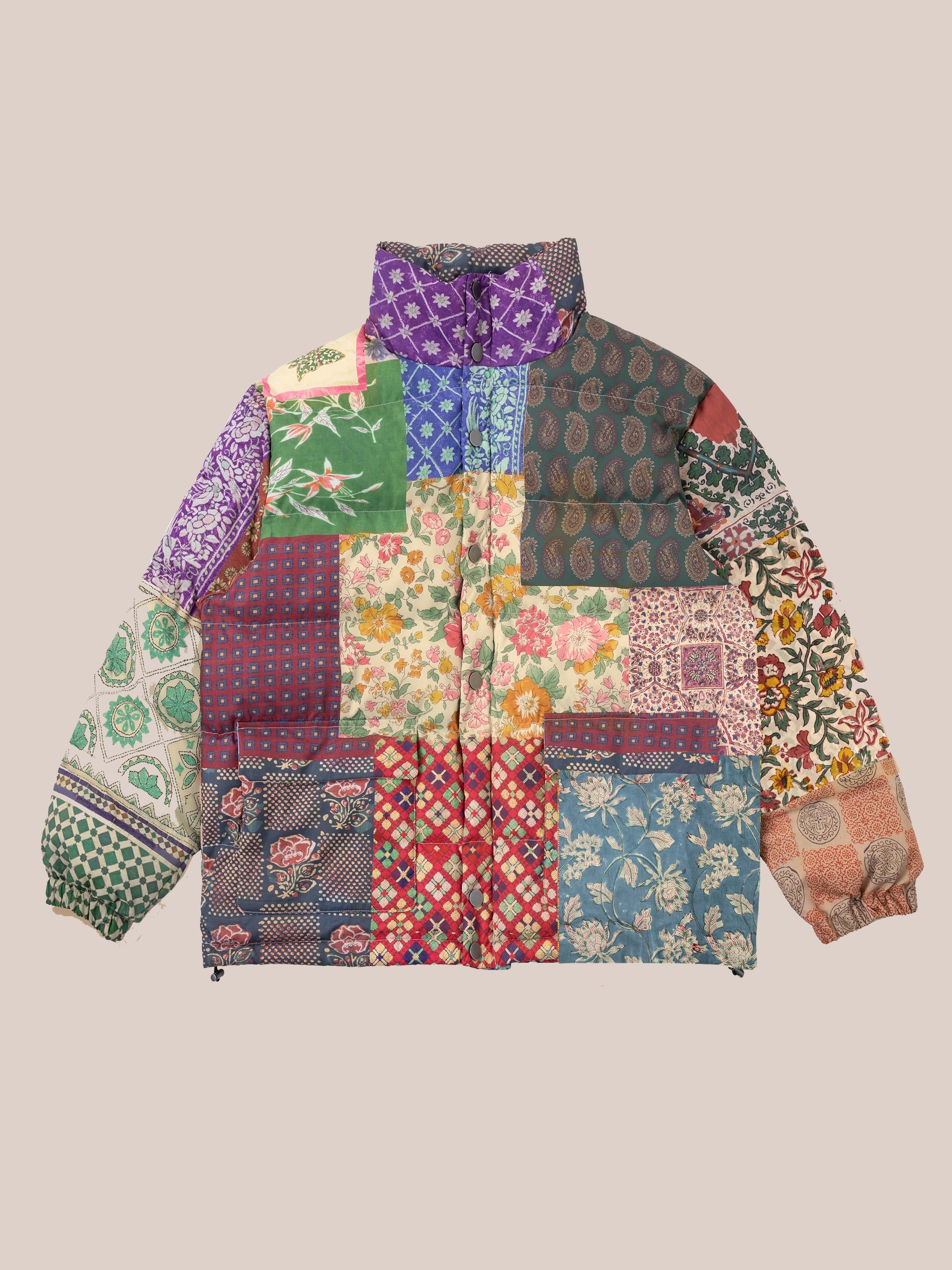 The Gardenia Tapestry Puffer Jacket by Found features a vibrant mix of floral and geometric patterns infused with traditional South Asian print elements, all set against a neutral background.