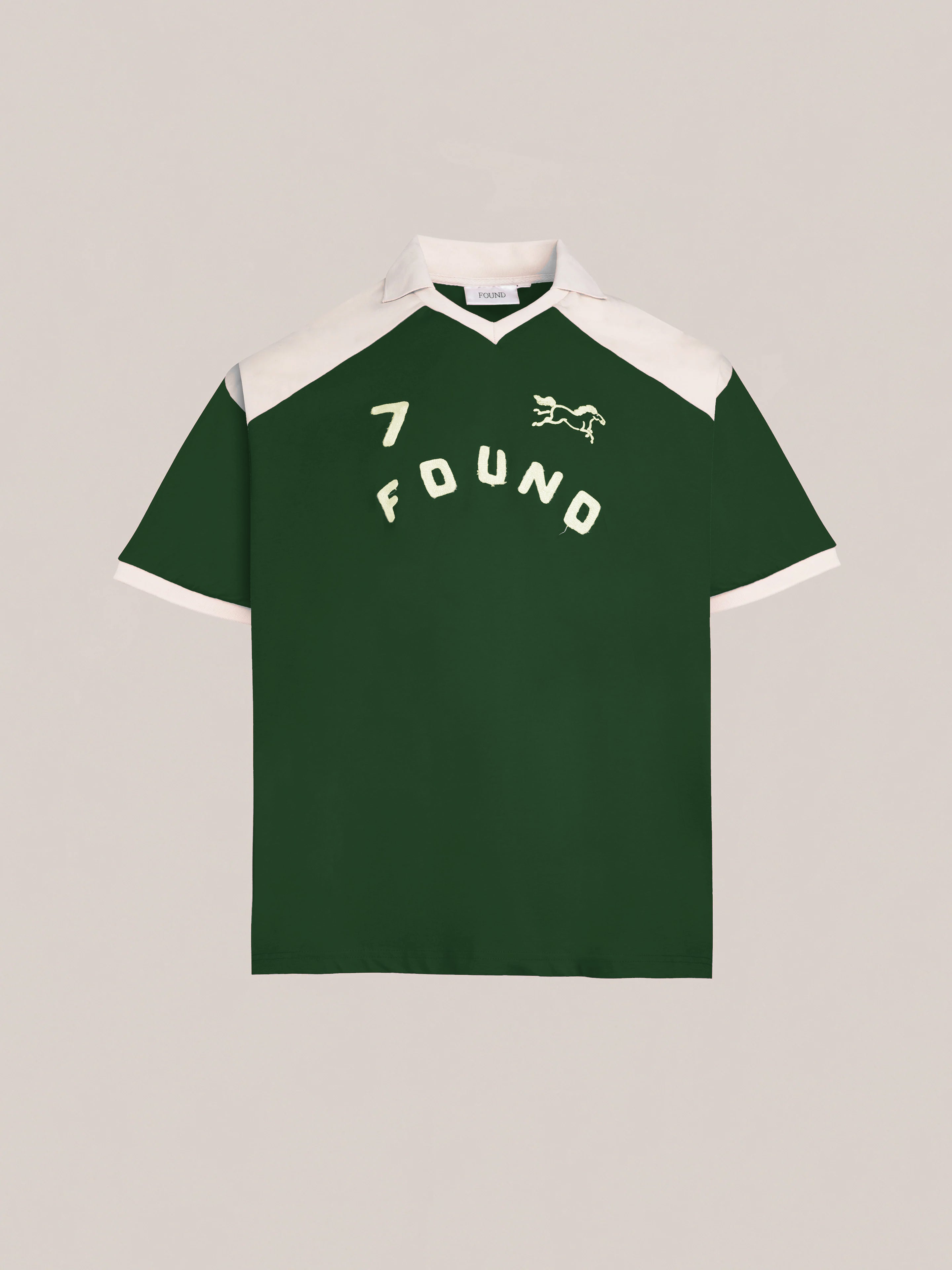 The Goji Green Jersey from FOUND exudes a vintage athletic uniform style, featuring a white collar and contrasting yoke. It is adorned with an embroidered number 7, the word "FOUND," and a small lion graphic on the front.