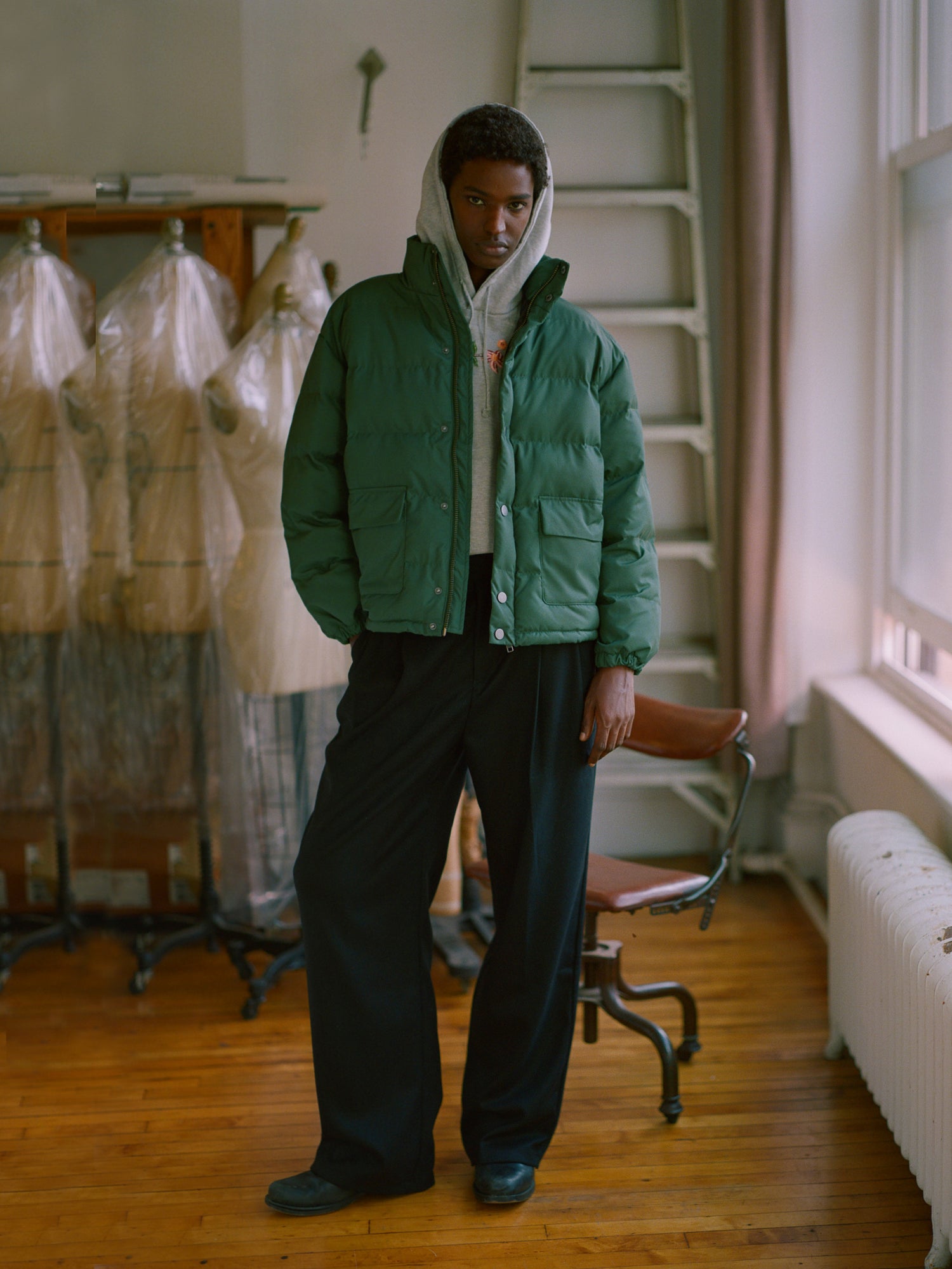 A man in a deep green puffer jacket, specifically the Found Laurel Pine Puffer Jacket, standing in a room.