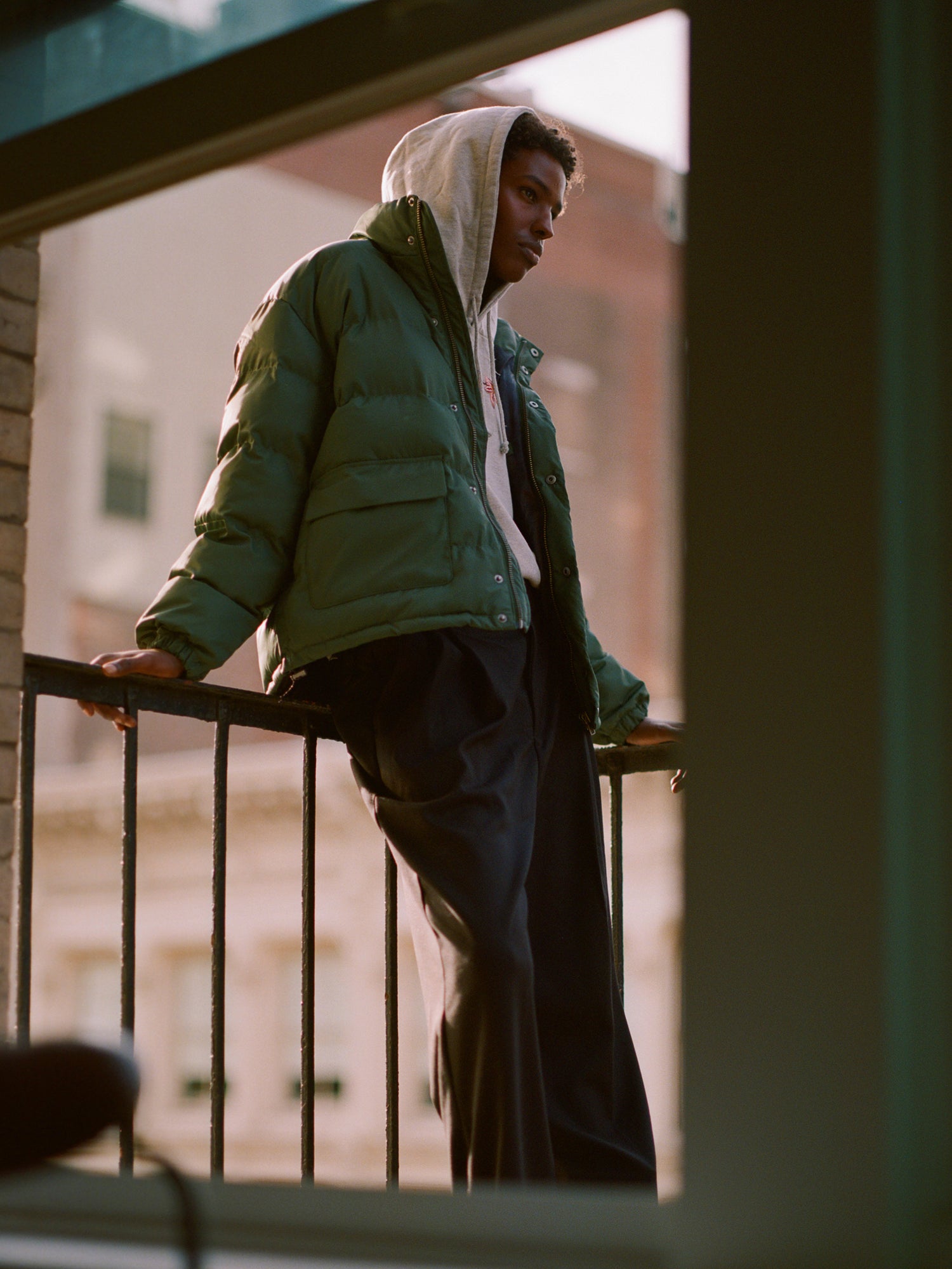 A man in a Found Laurel Pine Puffer Jacket standing on a balcony.