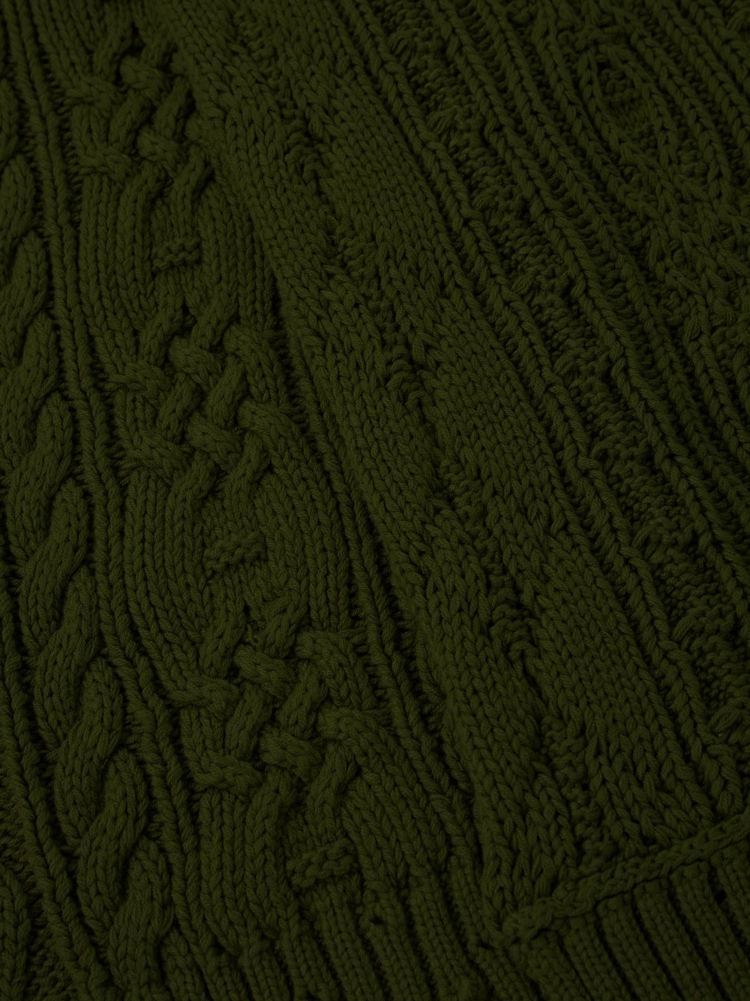 Close-up of the Forest Distressed Cable Knit Scarf by FOUND, showcasing its green fabric with various intricate cable patterns and textures.