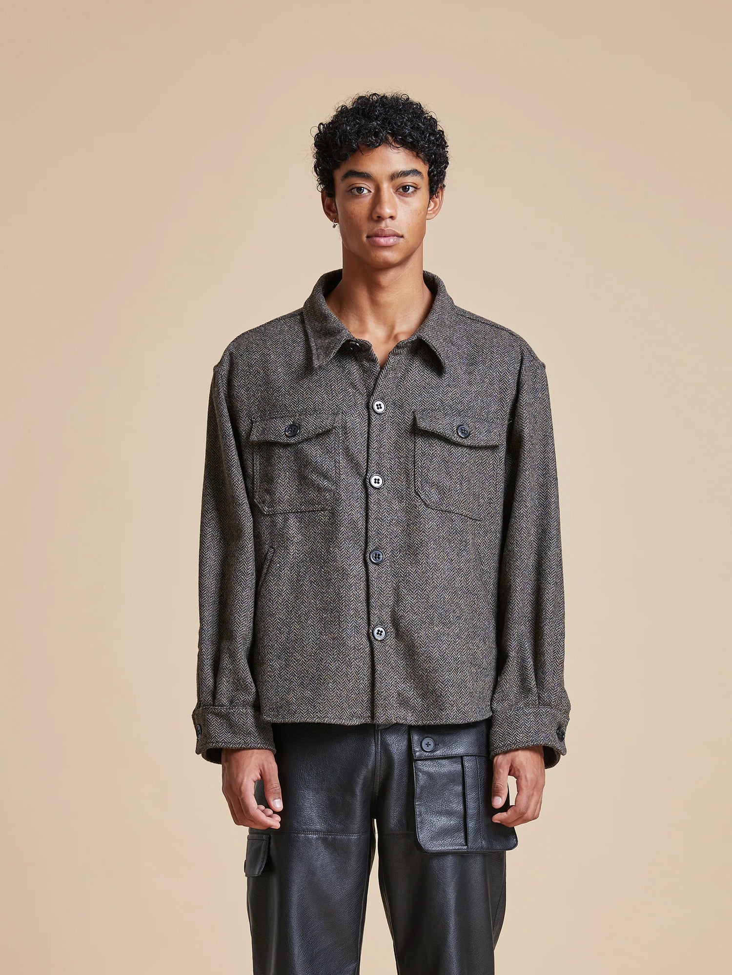 The model is wearing a Found Raven Herringbone Overshirt, a wardrobe staple for layering, with leather pants.