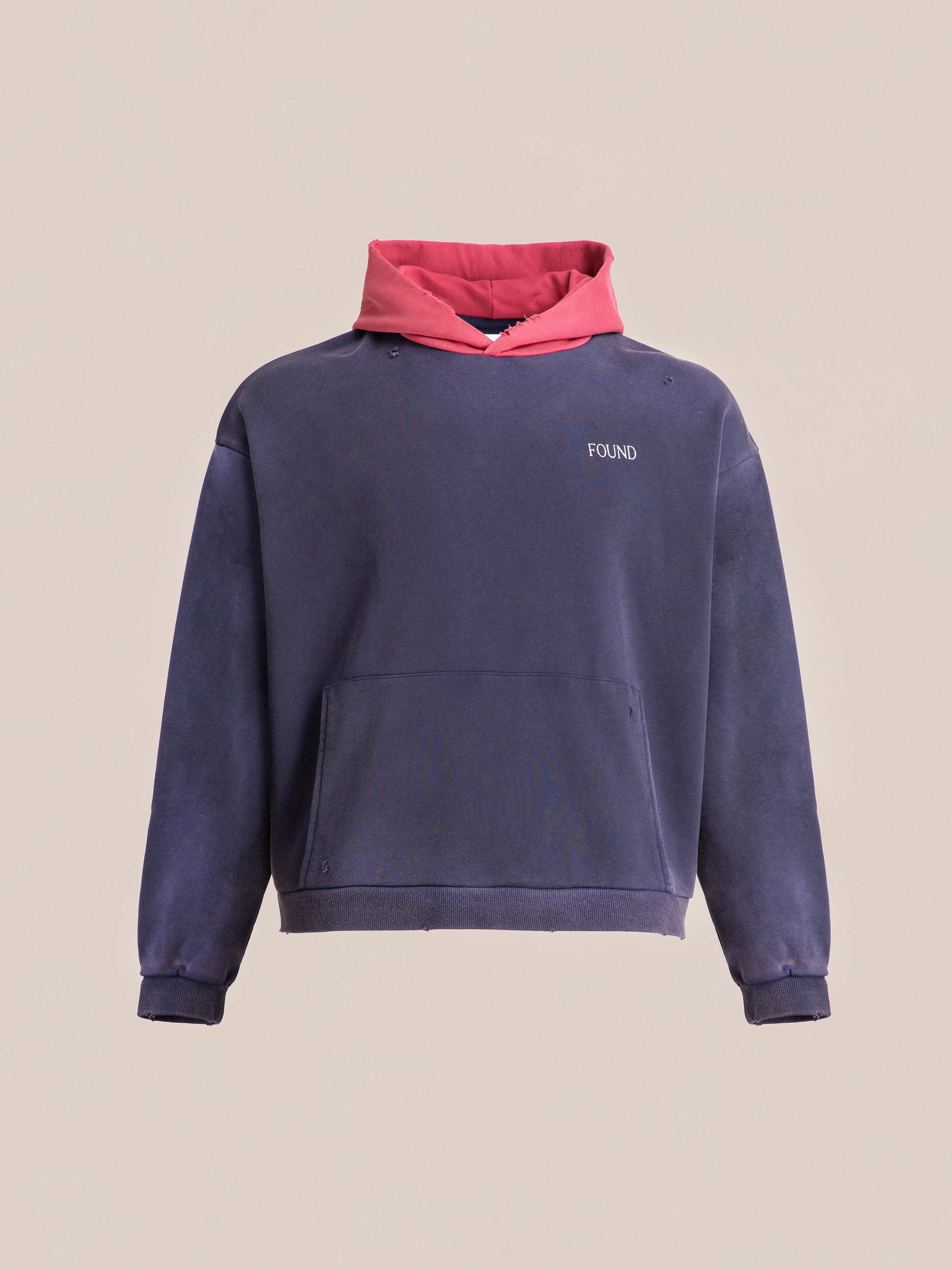 The Distressed Logo Hoodie by FOUND is a purple hoodie with a pink hood, crafted from soft French terry cotton, featuring a front kangaroo pocket. The word "FOUND" is embroidered on the chest, giving it a cozy vintage feel.