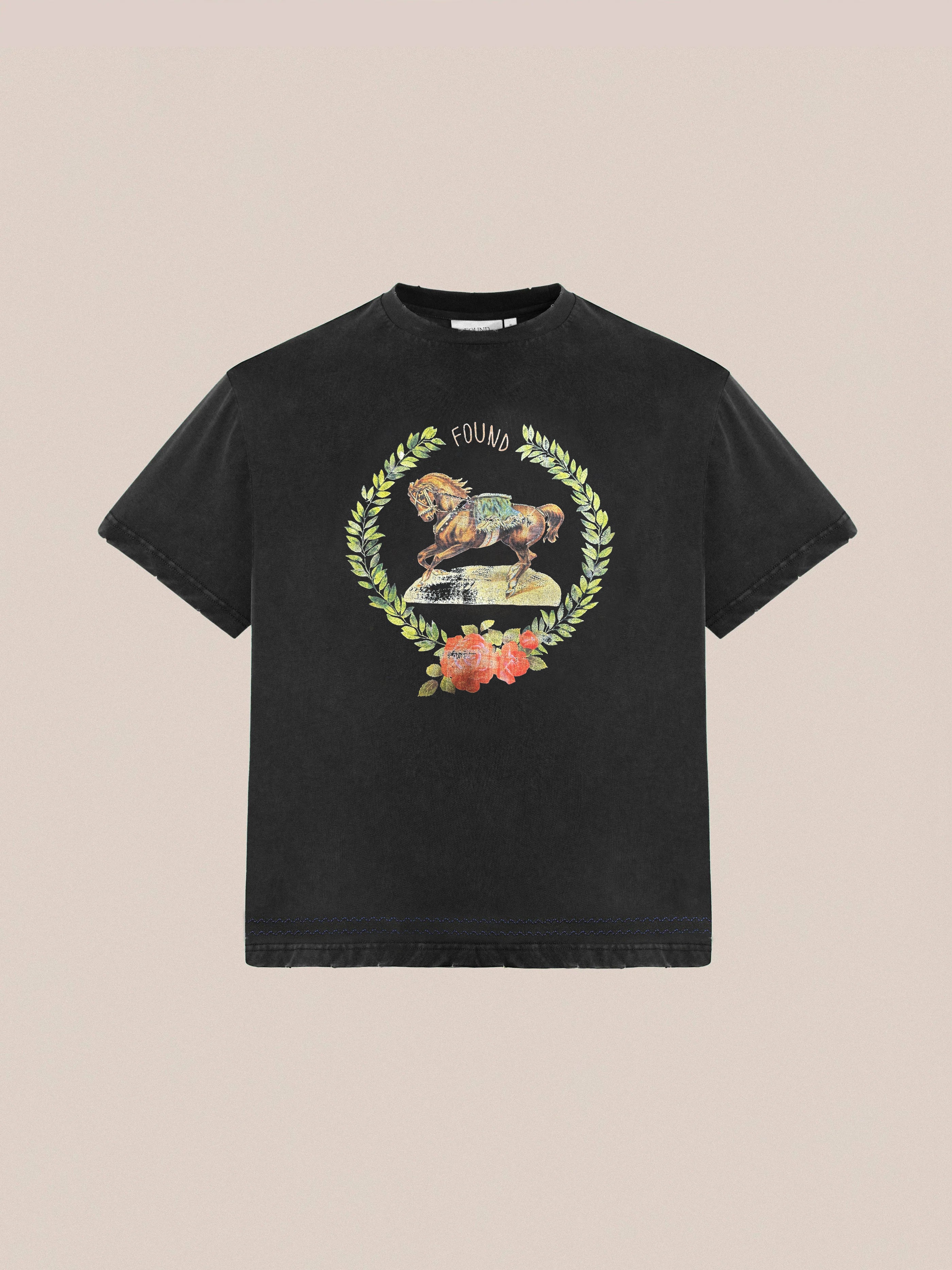 Check out the Rodeo Tee by FOUND, a black T-shirt designed with a vintage vibe featuring a lion, flowers, and "FOUND," all beautifully framed by a laurel wreath. Made from 100% cotton for supreme comfort and style.