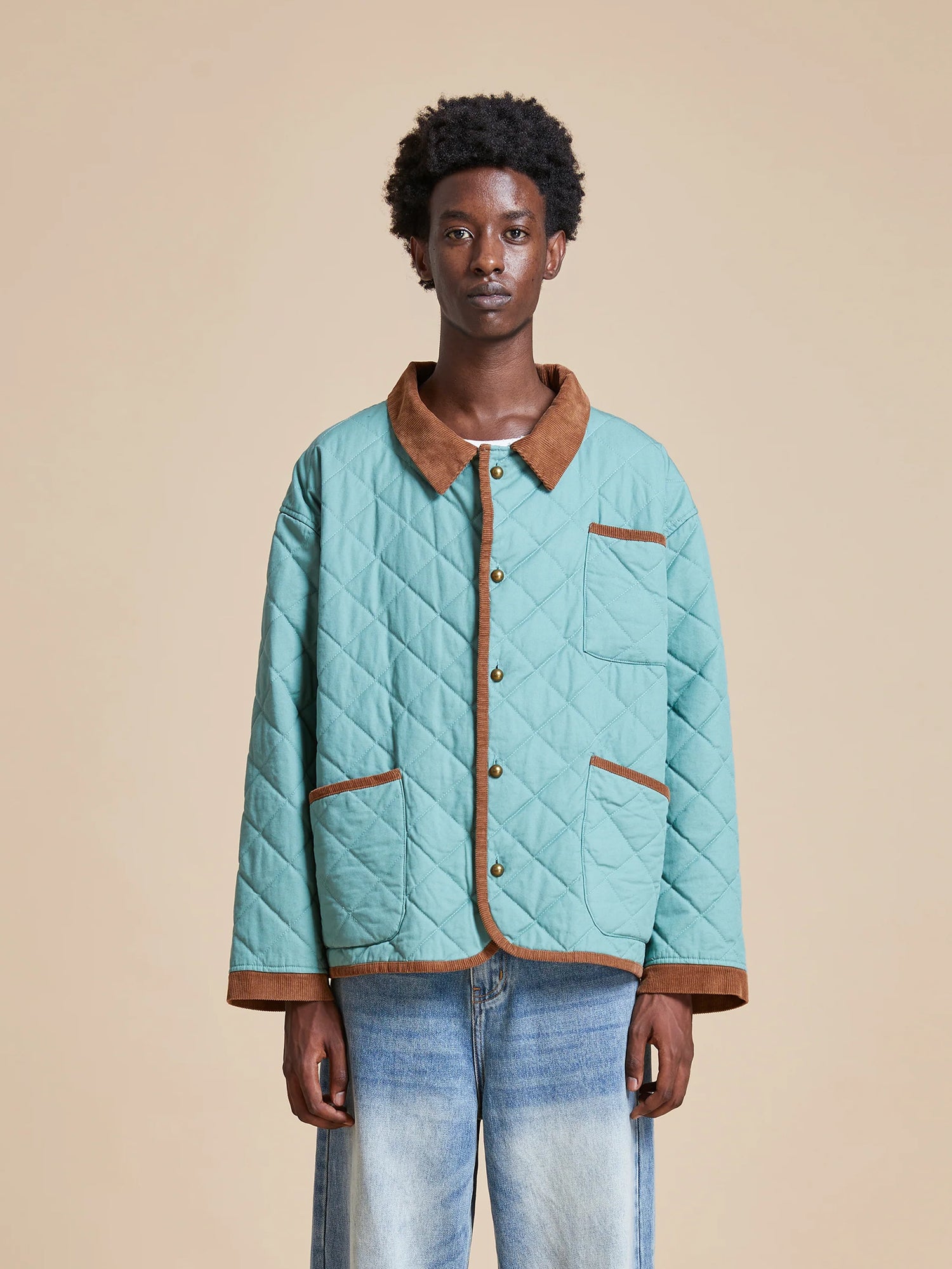 A man wearing a turquoise quilted Found Kashmir Meadow Quilt Jacket and jeans.