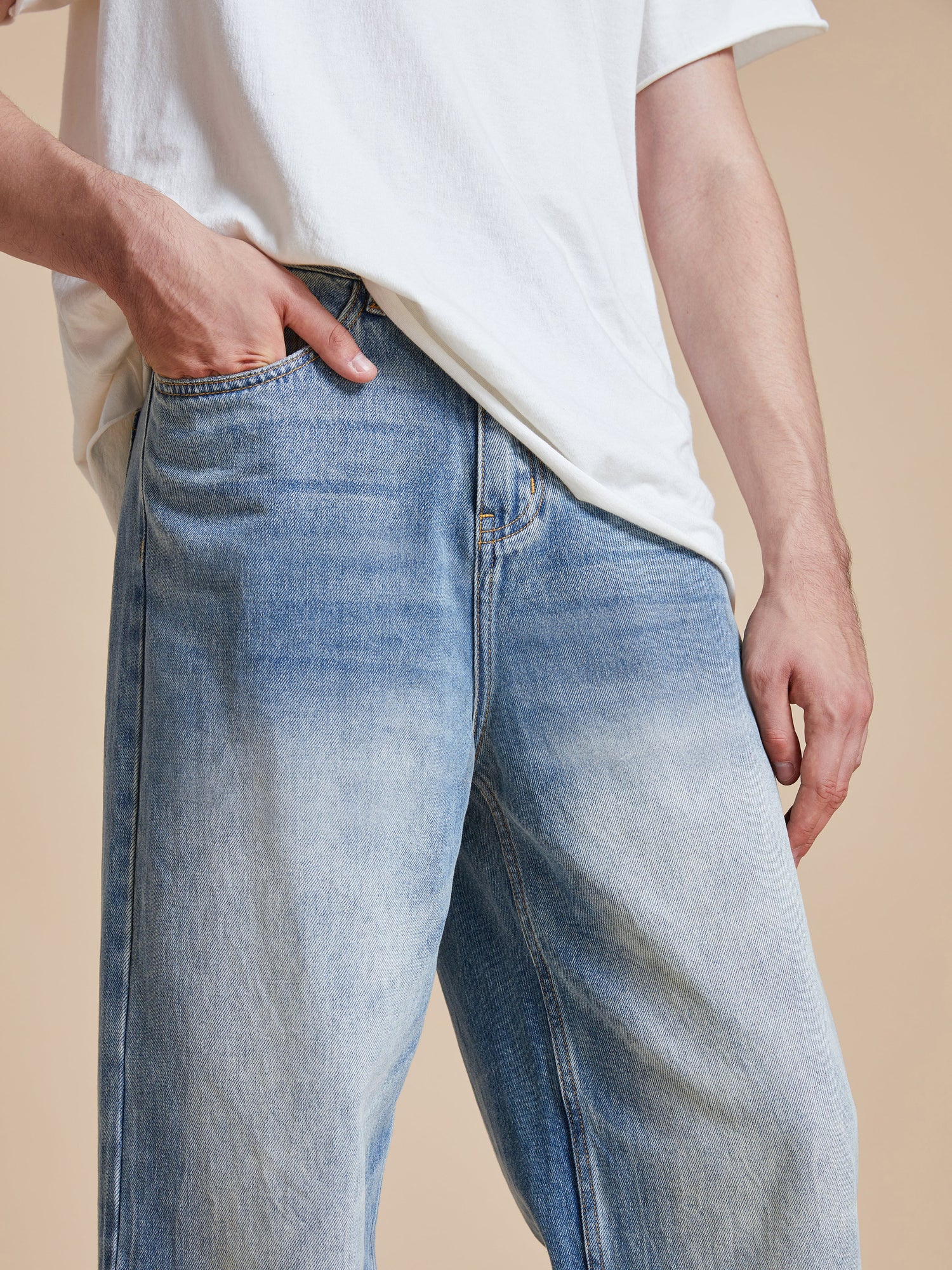 A man wearing a white t-shirt and Found vintage blue wash Lacy Baggy Jeans.