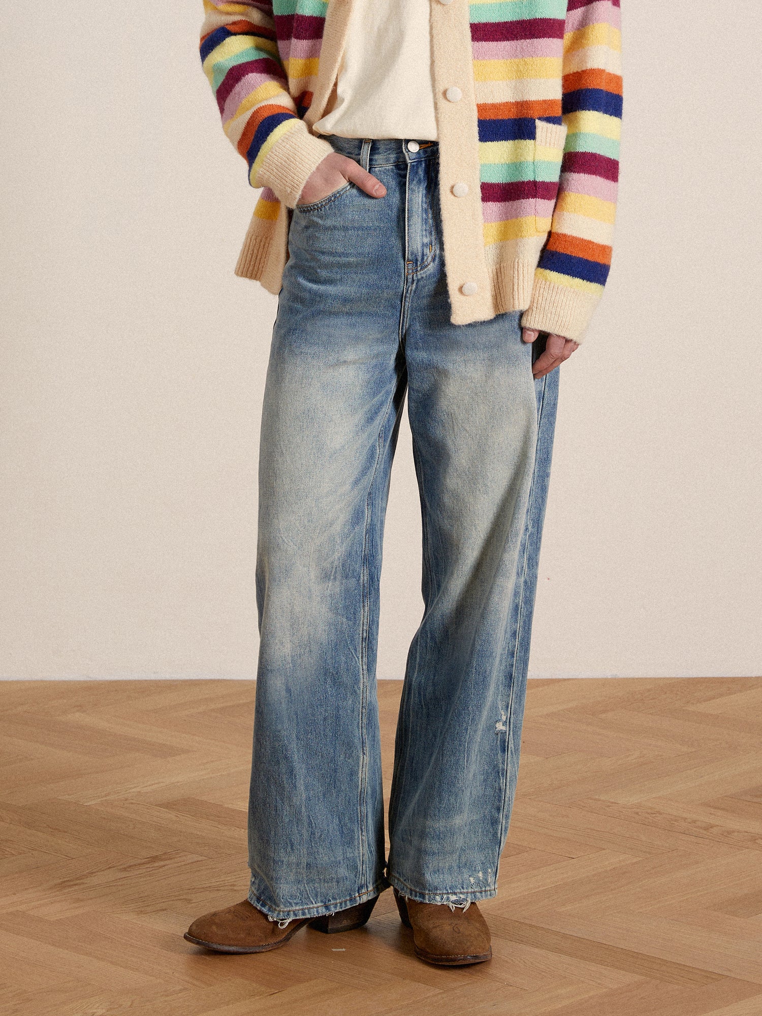 A person wearing Found's Lacy Baggy Jeans, striped sweater, and beige cardigan, standing in a room with wooden flooring.