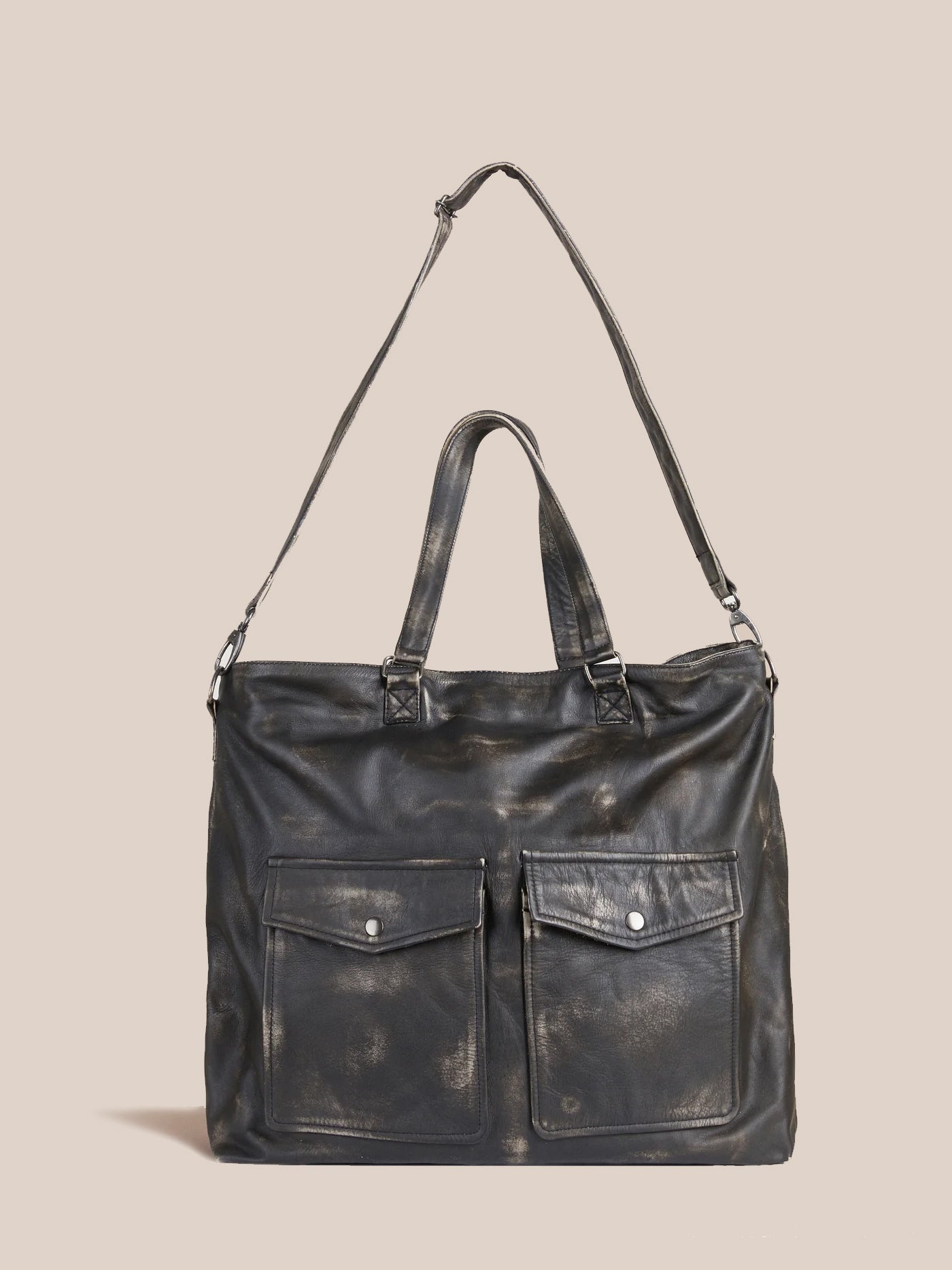 Profound's Hana Distressed Black Leather Bag, featuring a shoulder strap and two front pockets, is set against a plain beige background, making it a timeless statement piece.