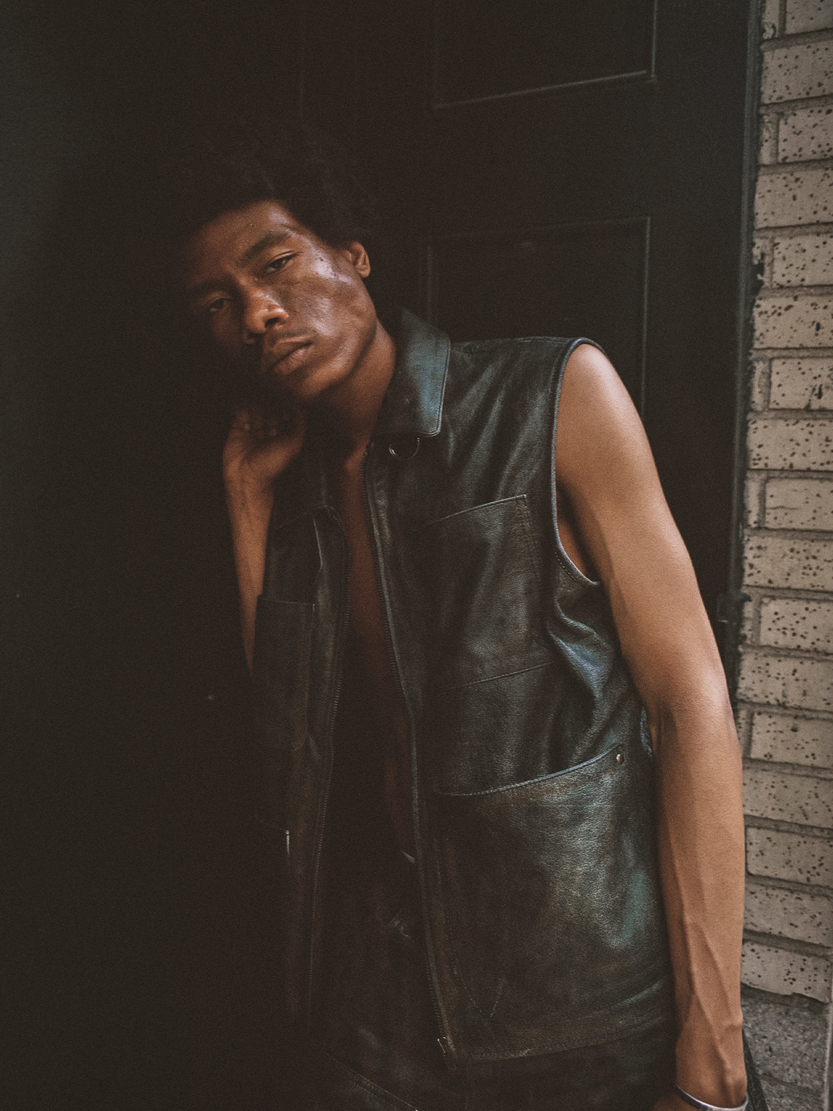 A person with short hair wearing the Found Distressed Genuine Leather Pocket Vest stands against a dark wall, looking directly at the camera.