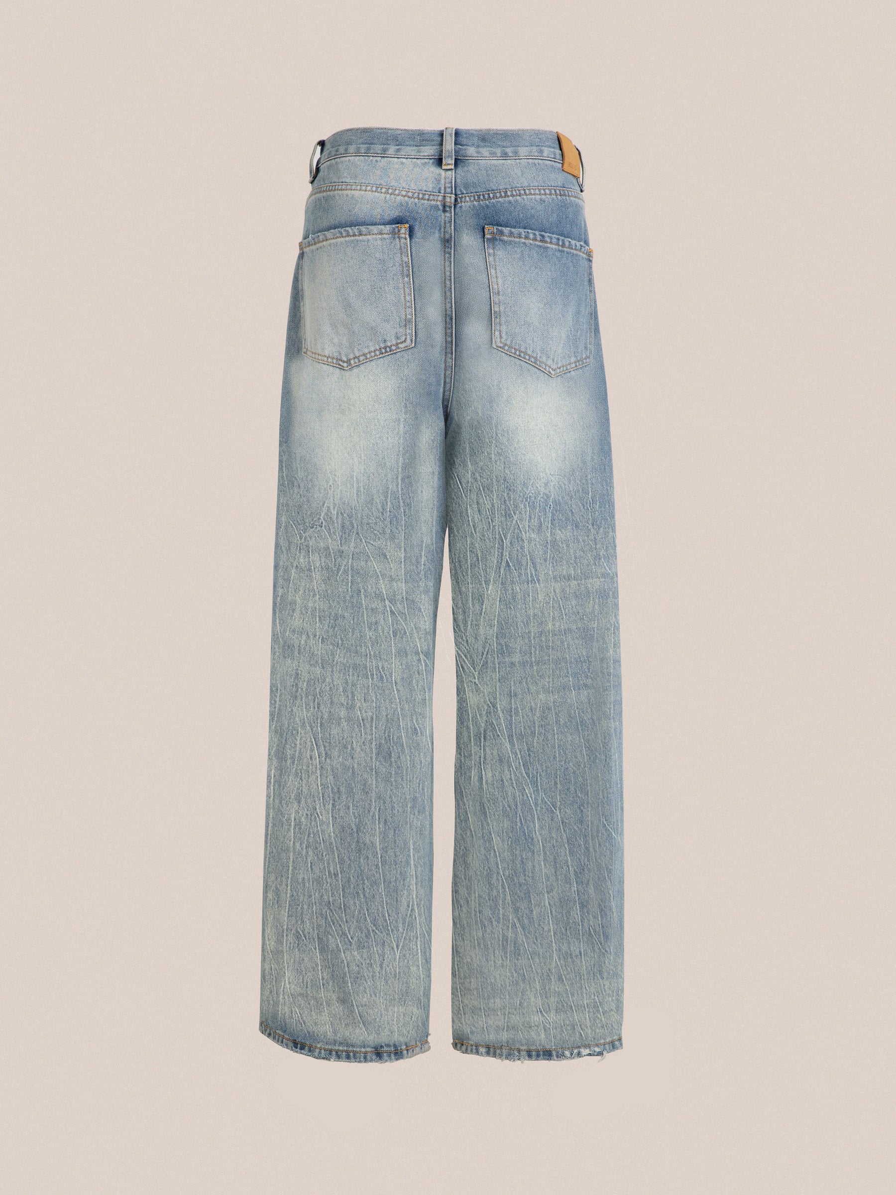 Back view of Found Lacy Baggy Jeans in light blue denim with a worn texture, showcasing two back pockets, distressed hems, and a tan leather patch on the waistband.