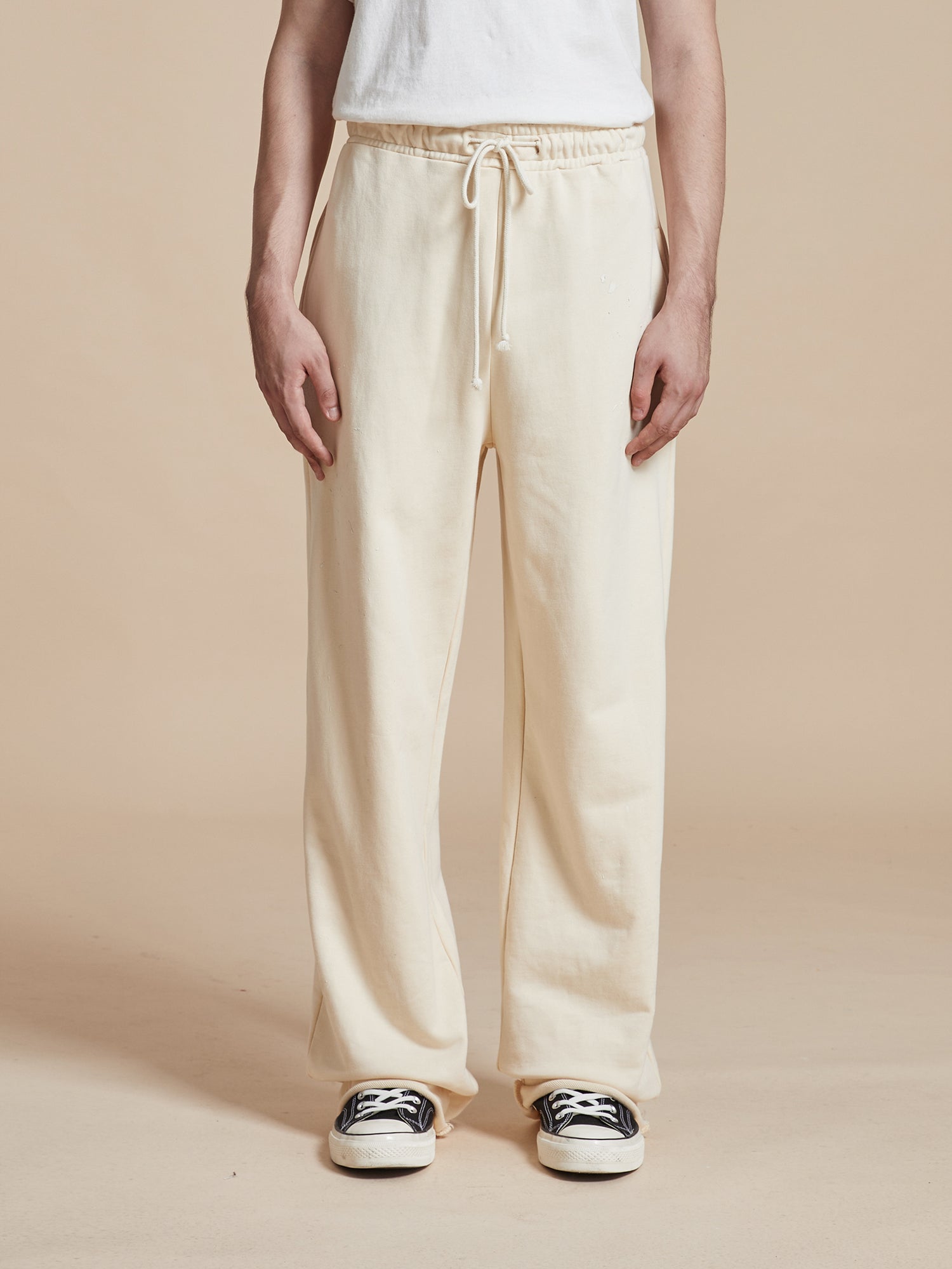 A man wearing a white t-shirt and sweatpants, including the wardrobe staple of Found Sandshell Lounge Pants.