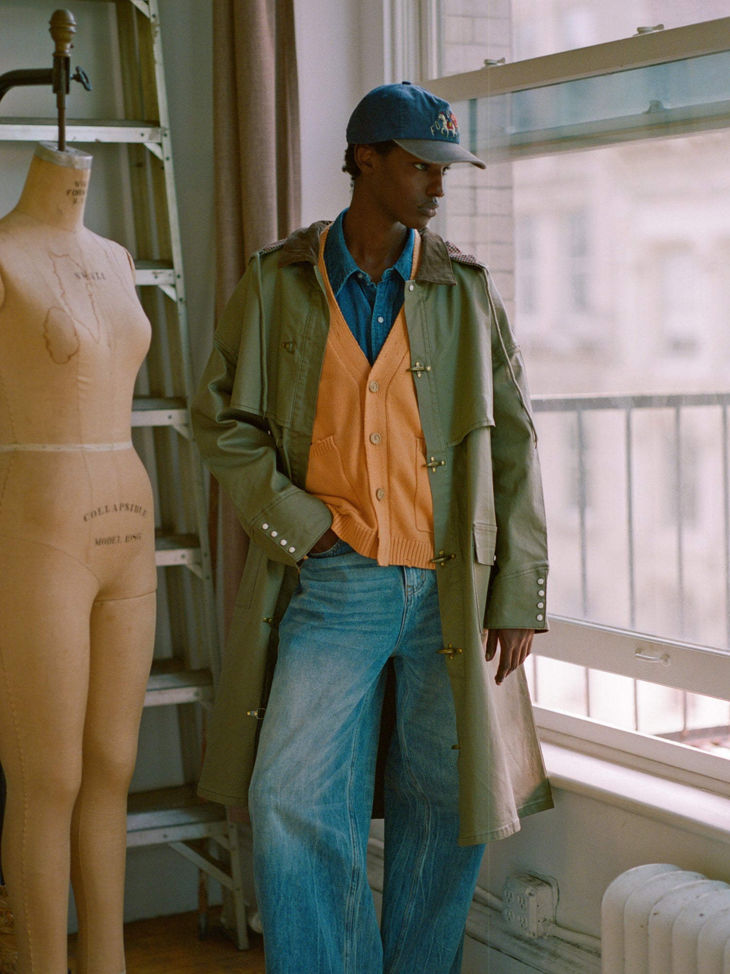 The model is wearing a yellow Cadmium Distressed cardigan and tan trousers.