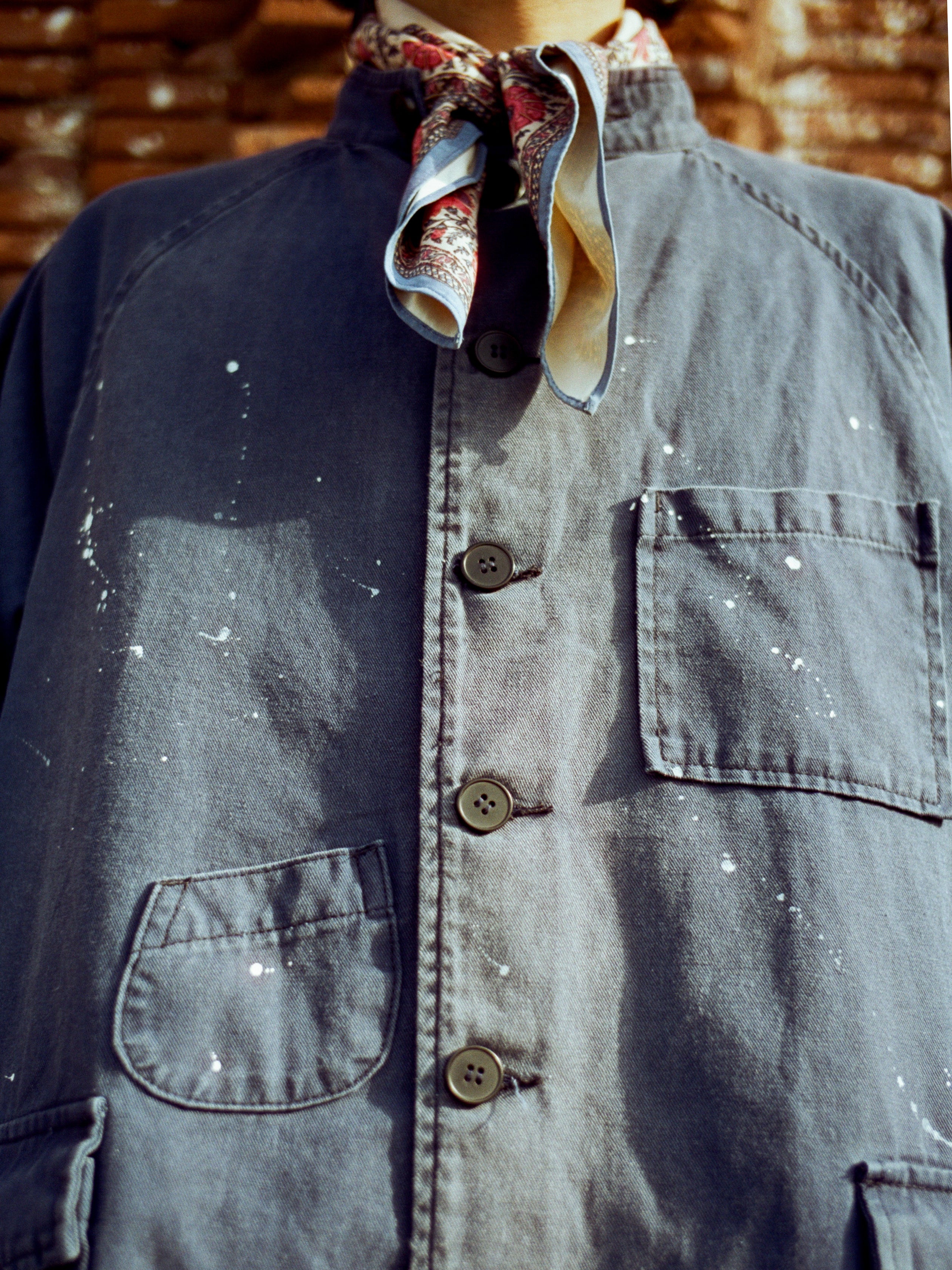 A man dressed in a Found River Painters Chore Coat with raglan shoulder, completes his ensemble with a tie.