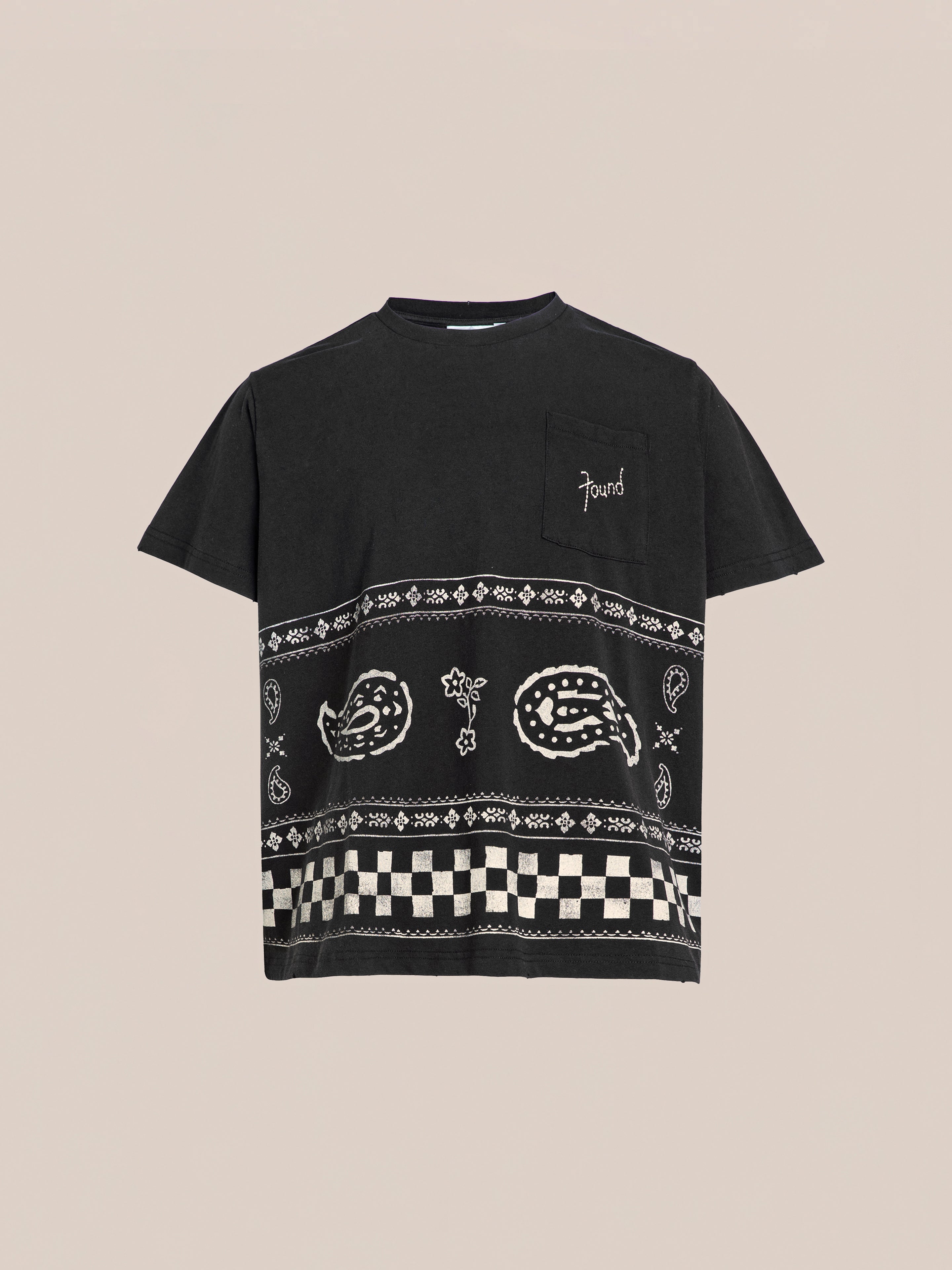 FOUND's Ornament Pocket Tee is a black t-shirt featuring a chest pocket and decorative white patterns including paisley designs and checkered stripes on the lower half.