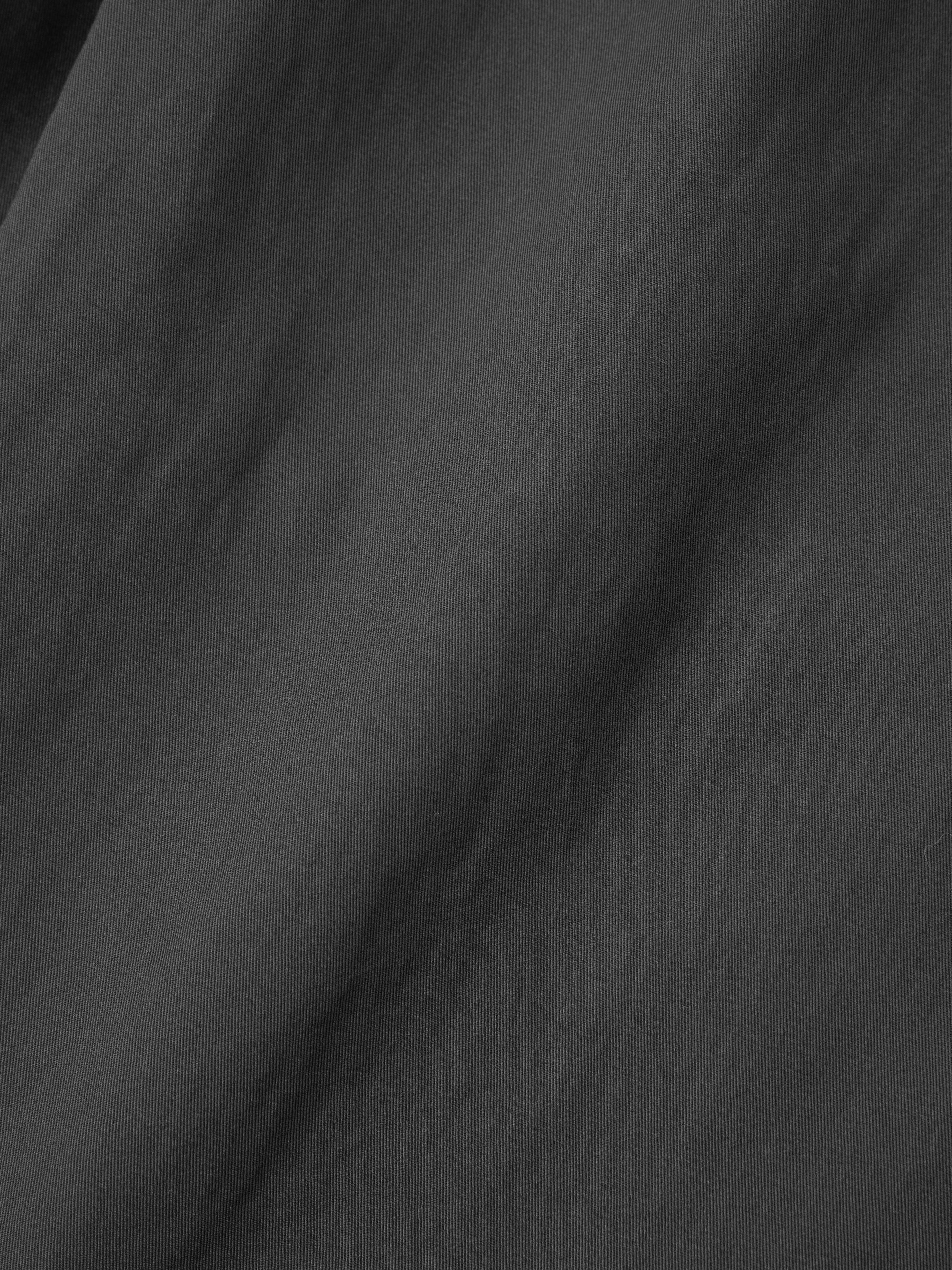 Close-up of a textured black fabric with soft folds and slight sheen, reminiscent of the wide leg design found in the Parachute Cargo Twill Pants by Found.