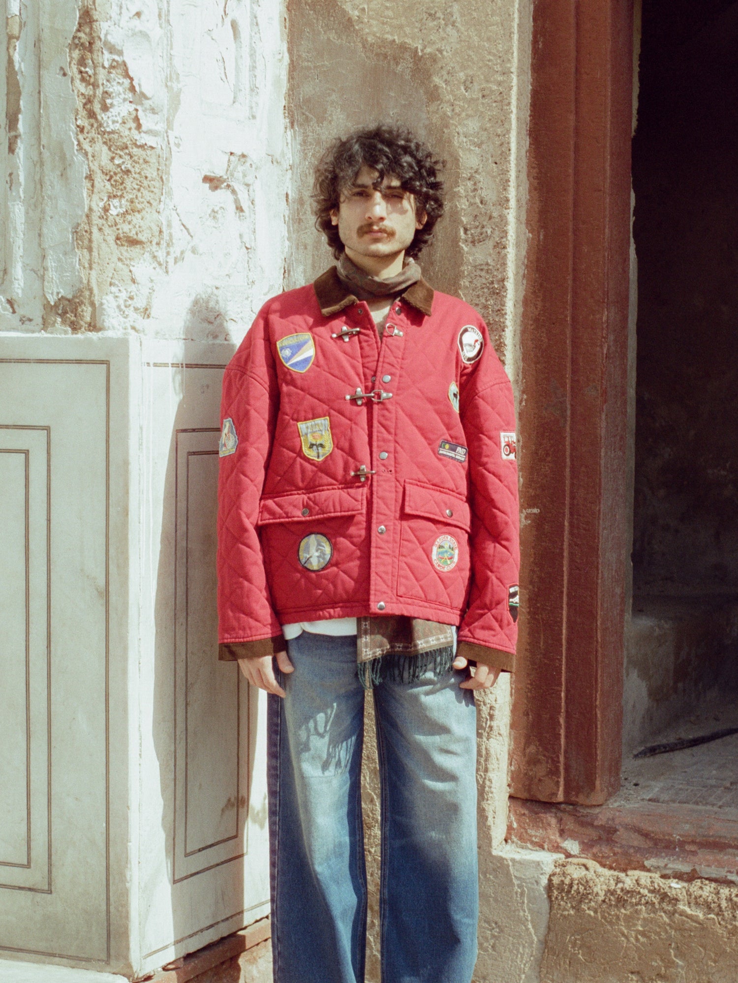 A man wearing a Found Farmstead Quilt Patch Jacket, featuring vintage hunting competition jackets, and jeans.