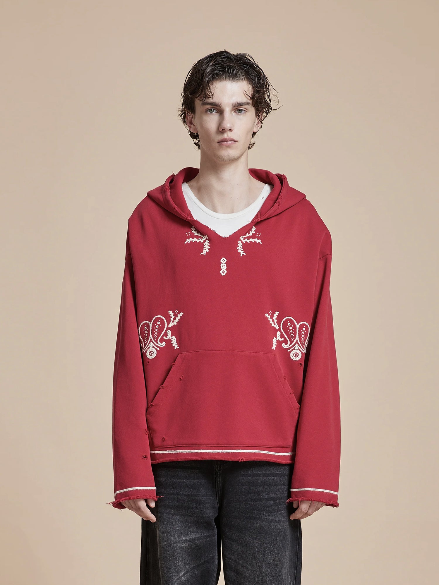 A man dressed in a red Found Phulkari Embroidered Hoodie and black pants adorned with Phulkari embroidery, showcasing the rich heritage of the Punjab region.