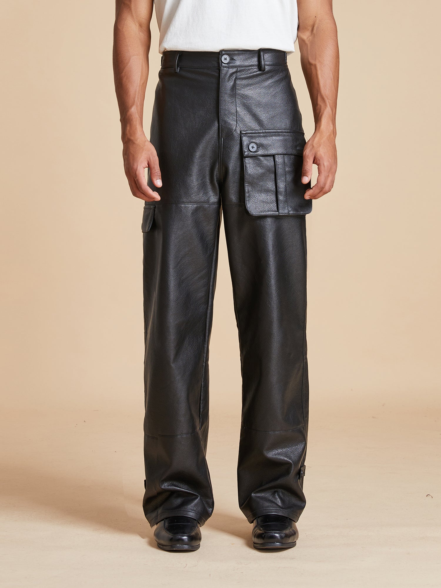 A man wearing Found faux leather cargo pants with cargo pocket placements.