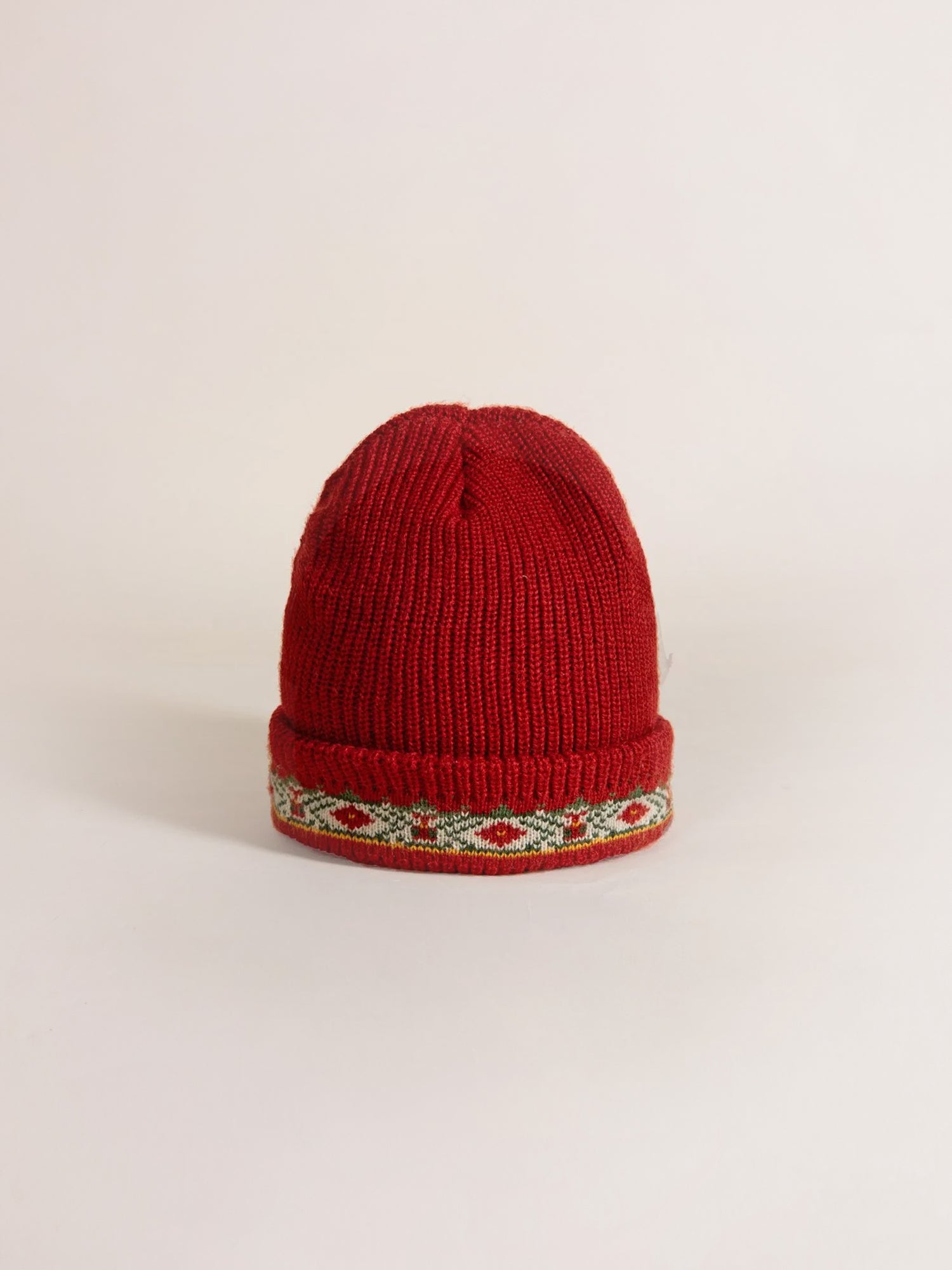 The Ajrak Beanie by Profound is a red, chunky knit beanie featuring a folded brim and a decorative green-and-red patterned band. Crafted from soft cotton for ultimate comfort.