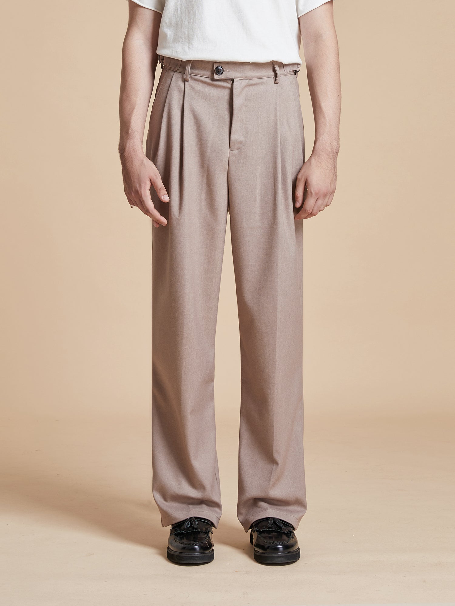 A man wearing a white t-shirt and beige Pleated Trousers with a classic silhouette from Found.