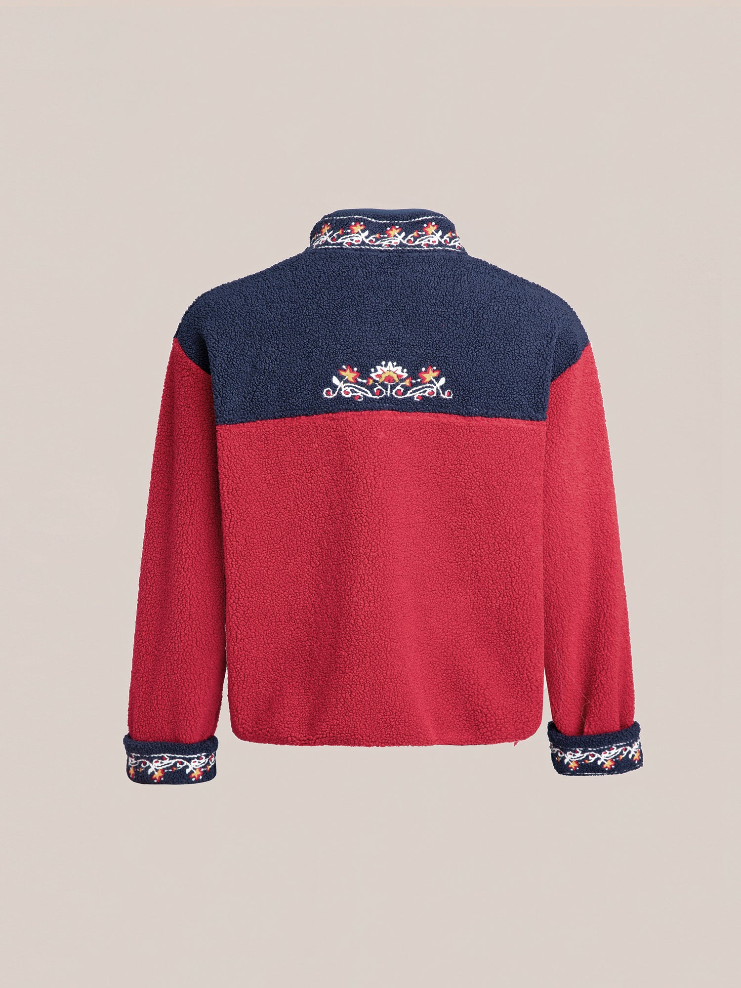 A Pahari Floral Embroidered Sherpa Pullover by FOUND, featuring a red body, navy shoulders and collar, with Pahari style embroidery on the upper back and cuffs.