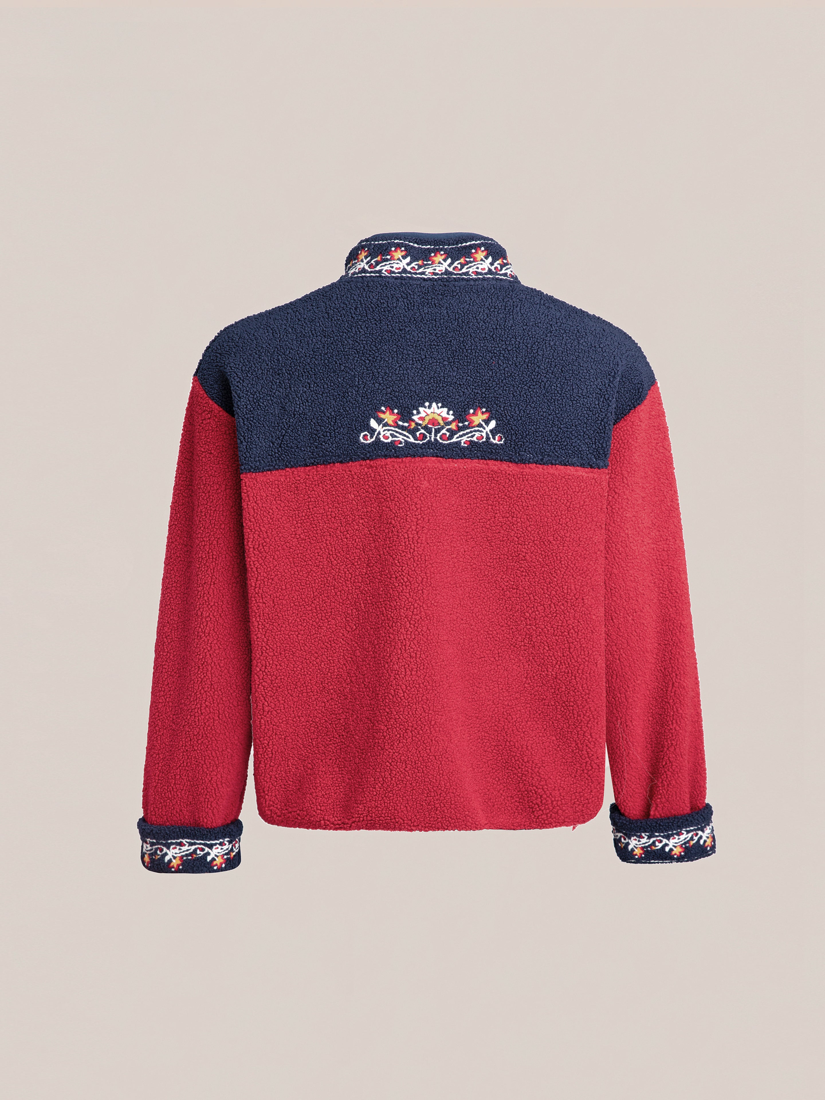 A Pahari Floral Embroidered Sherpa Pullover by FOUND, featuring a red body, navy shoulders and collar, with Pahari style embroidery on the upper back and cuffs.