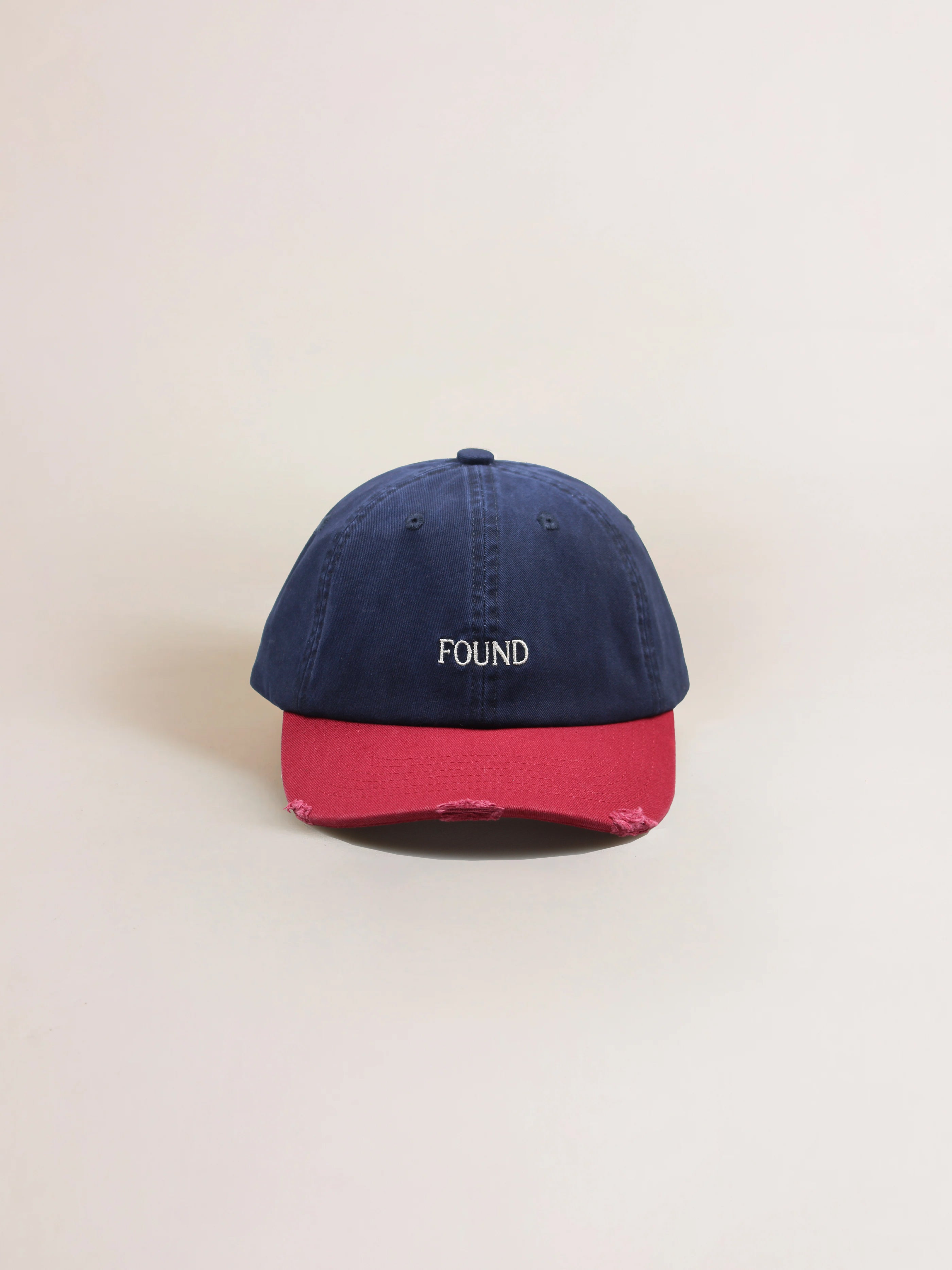 The Two-Tone Logo Cap by FOUND is a sleek cotton hat, featuring the bold FOUND logo in a vibrant blue and red design that stands out against a plain background.