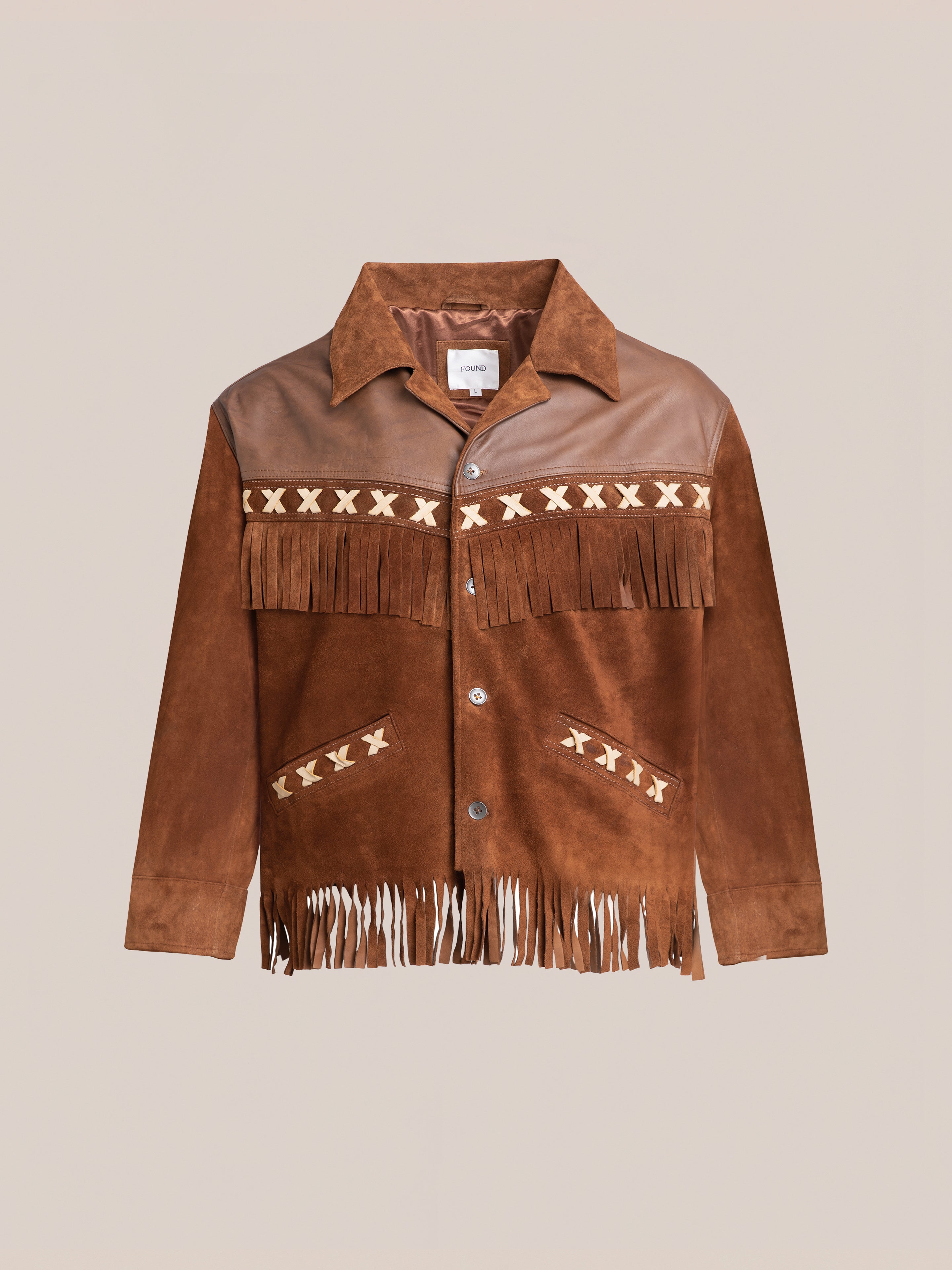 The Western Fringe Suede Jacket by FOUND features a brown suede fringe design with button closure, adorned with darker leather patches and white cross patterns on the chest and pockets. Crafted from two-tone suede and leather, this piece is made from ethically sourced materials.