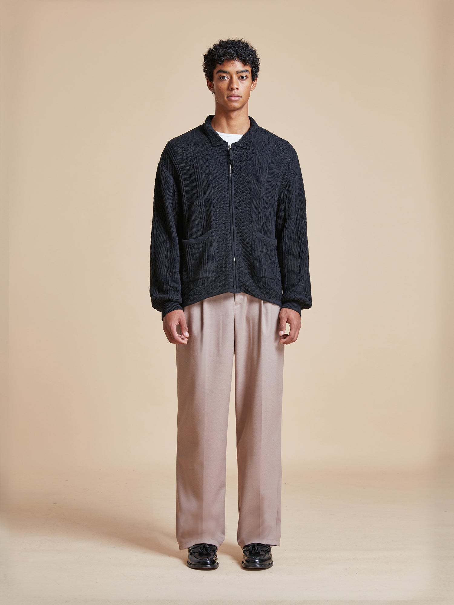 The model is wearing a Found Zip Up Panel Knit Ribbed Sweater and beige pants.
