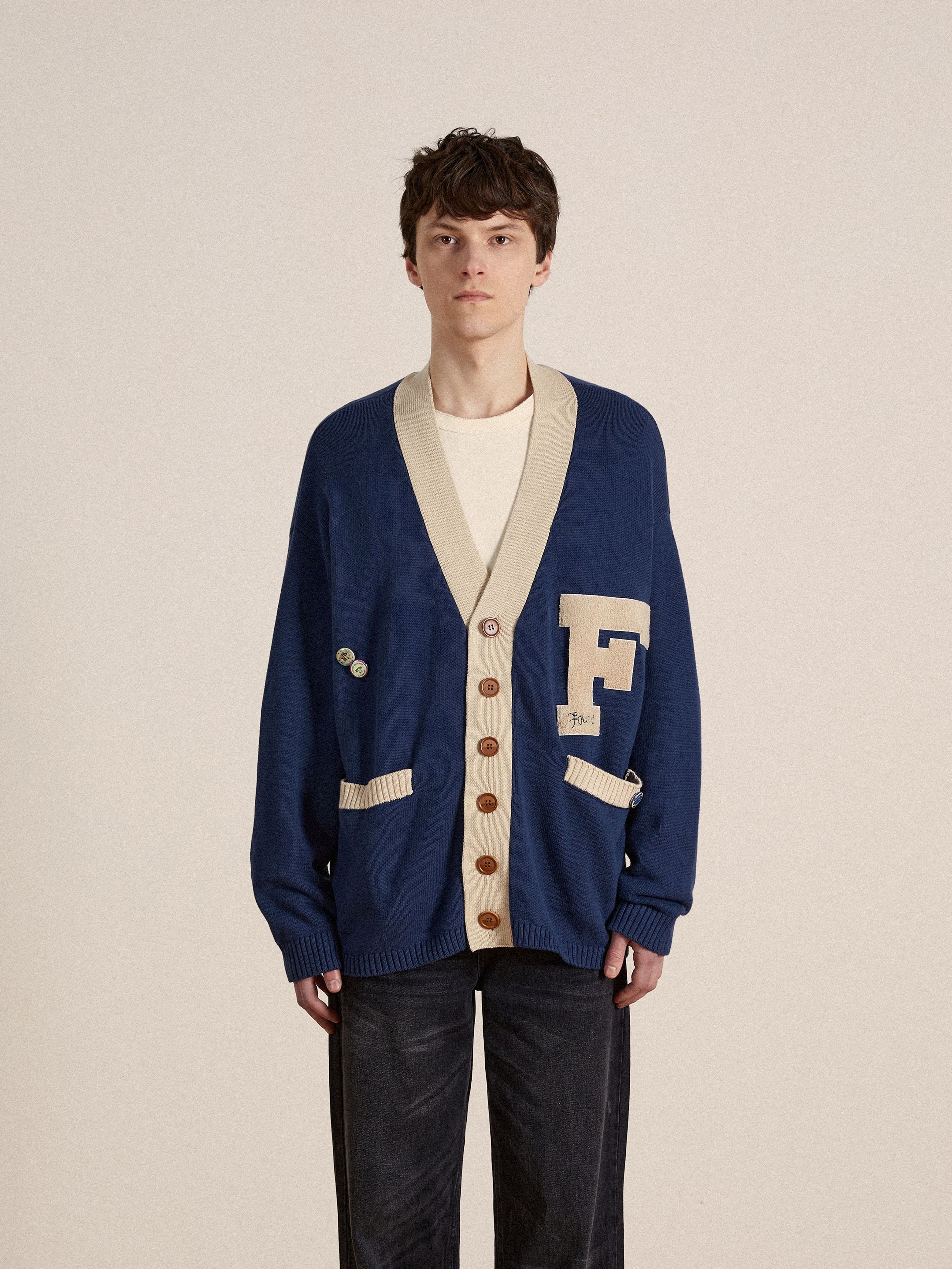 A man in a customizable Found Laleh Varsity Contrast Cardigan.