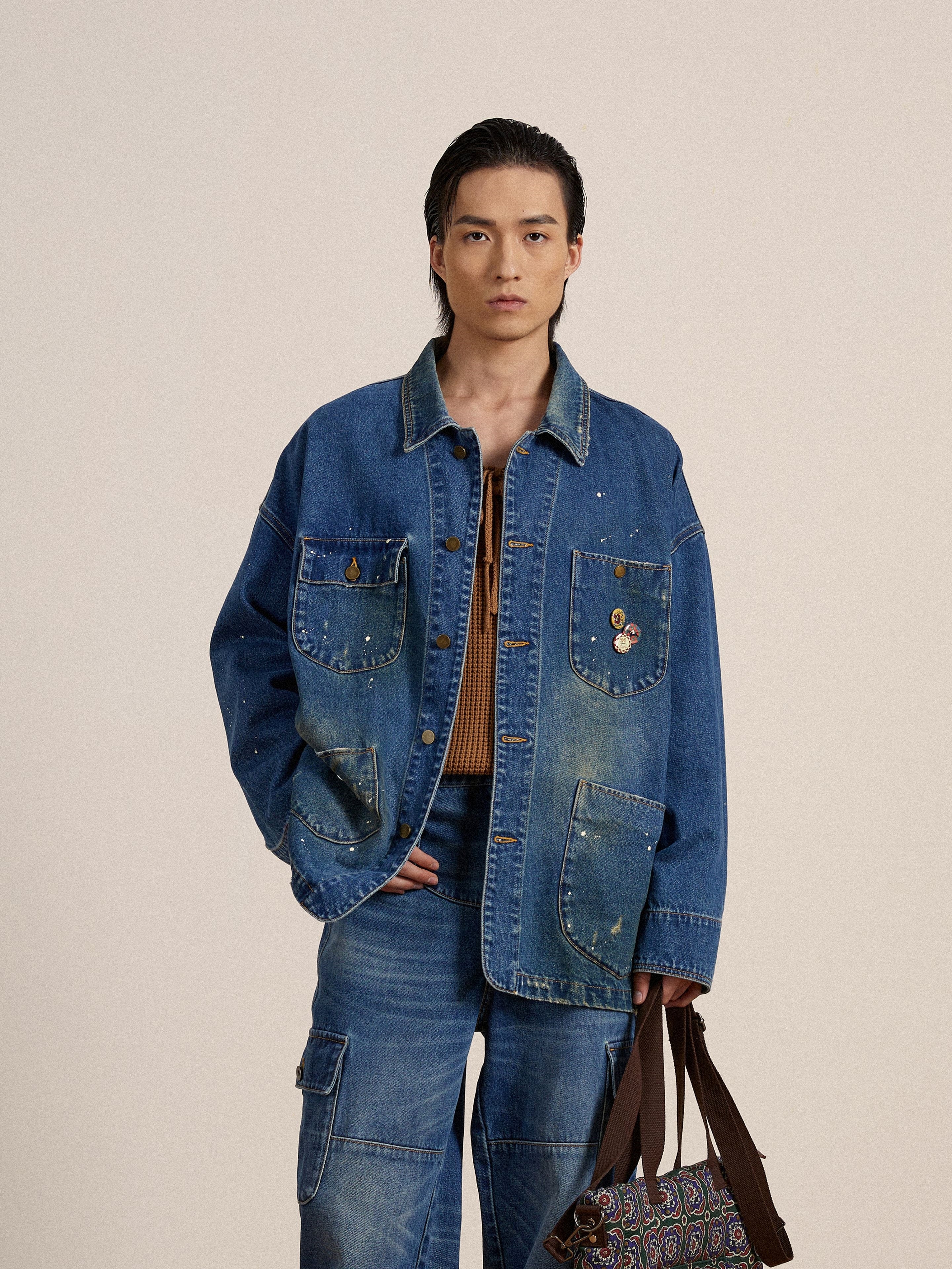 An artist in a Kavir Denim Painter Jacket by Found holding a bag.